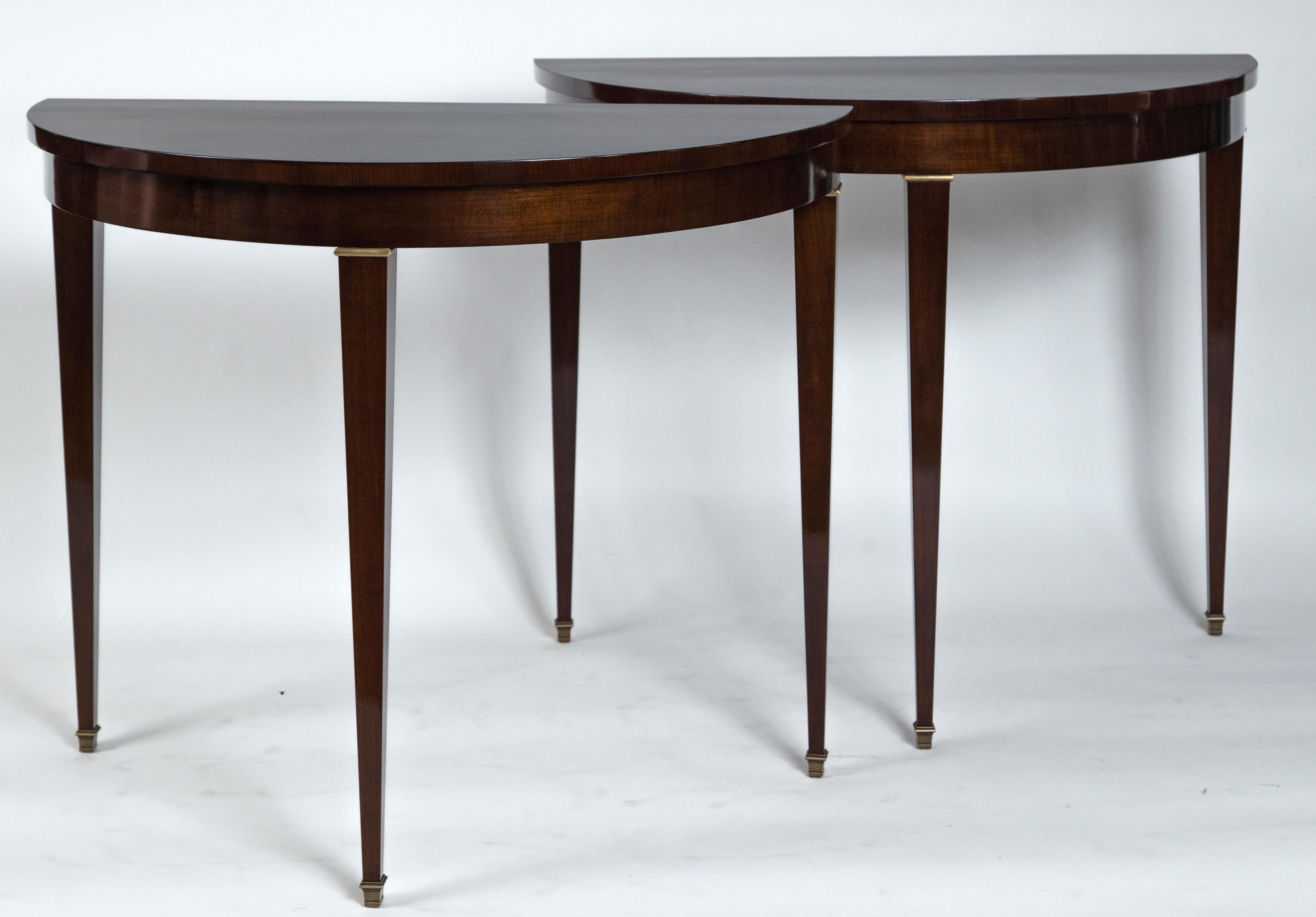 Handsome pair of Italian demilune-shaped consoles finishing on straight tapered legs with brass sabot and brass fittings, tables in a dark cherrywood veneer.
Priced by the pair.
Origin: Italy
Period: circa 1950
Condition: Excellent, refinished