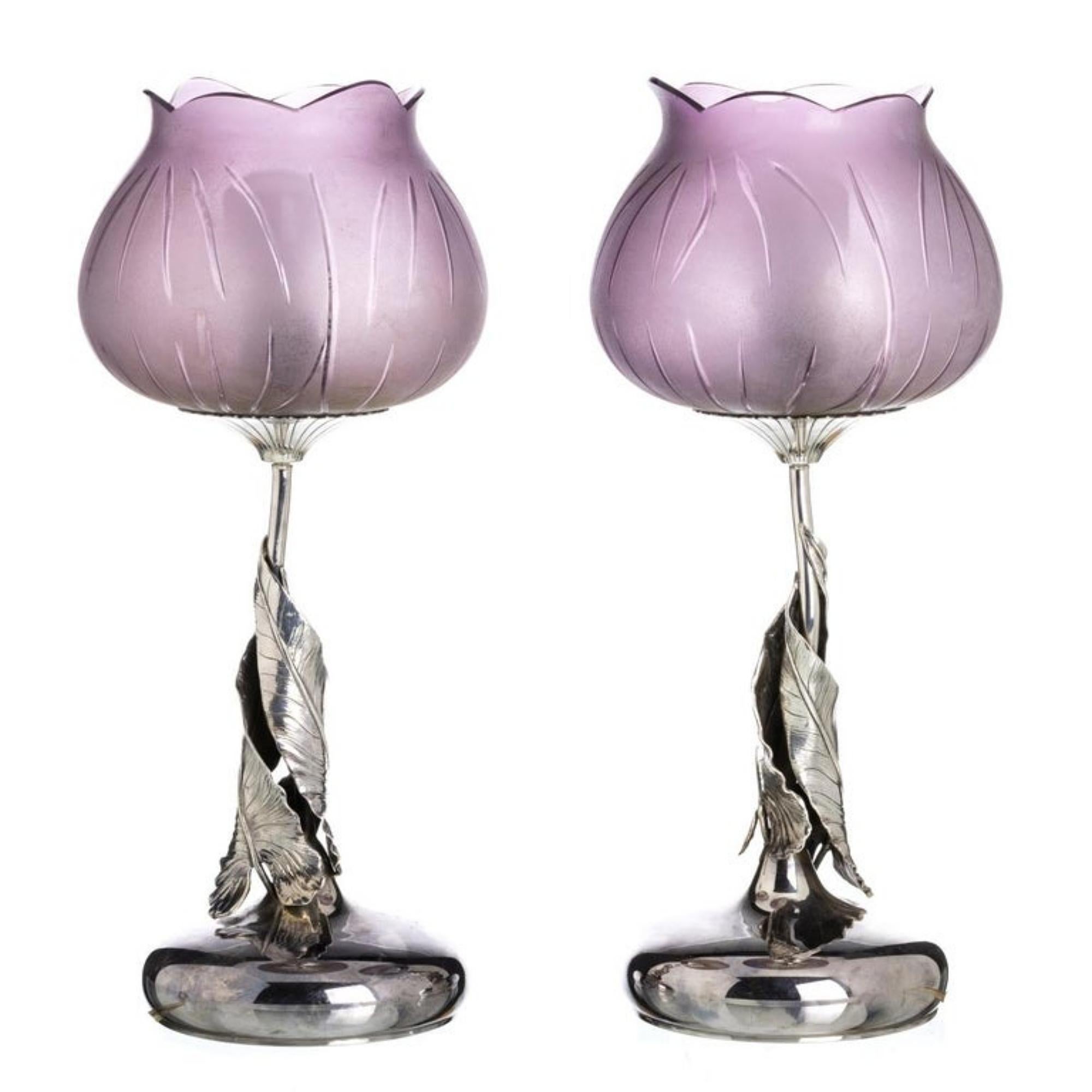 Pair of Italian Art Nouveau silver and glass lamps.
20th century, 
Art Nouveau style, with circular bases with stem with foliage of vases and bells in lilac glass. 
Marked with 925 thousandths. 
Dim. Height: 40 cm.