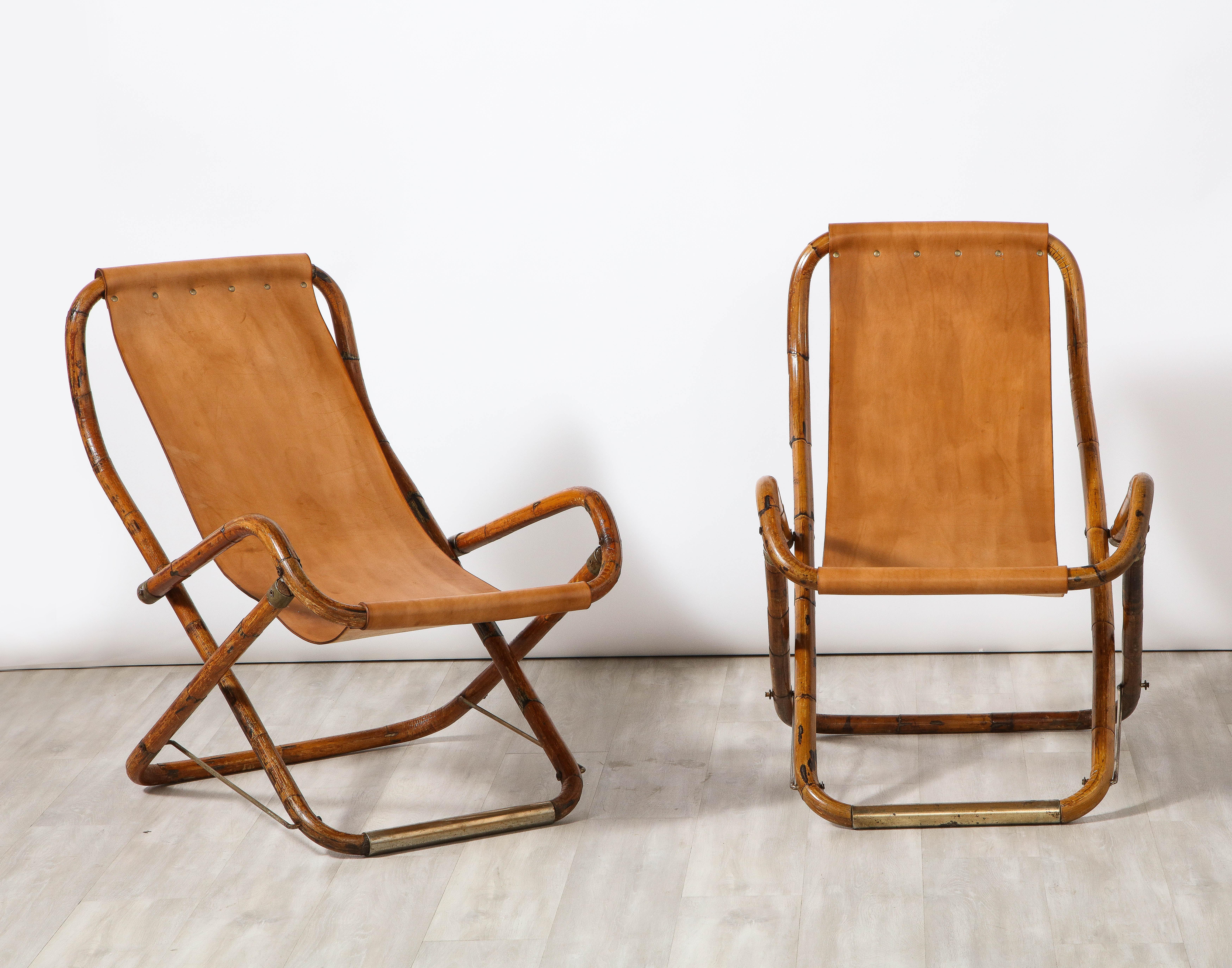 Gianfranco Frattini for Bernini pair of Italian folding campaign chairs, comprised of bamboo with brass stretchers and detailing and caramel leather sling seats. (The chairs fold with leather straps). Chic addition to the city or country! 
Designed