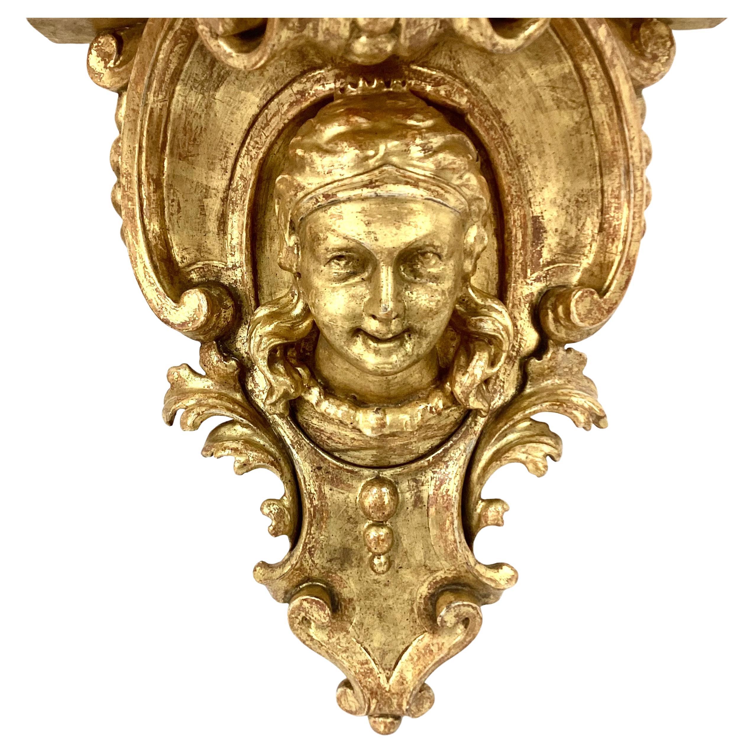 Unique pair of 19th century Italian baroque revival gilt wood wall brackets. A serpentine shelf lies over a c-scrolling foliate wall plate carved with 1) a maiden's bust and 2) a devil's bust. 