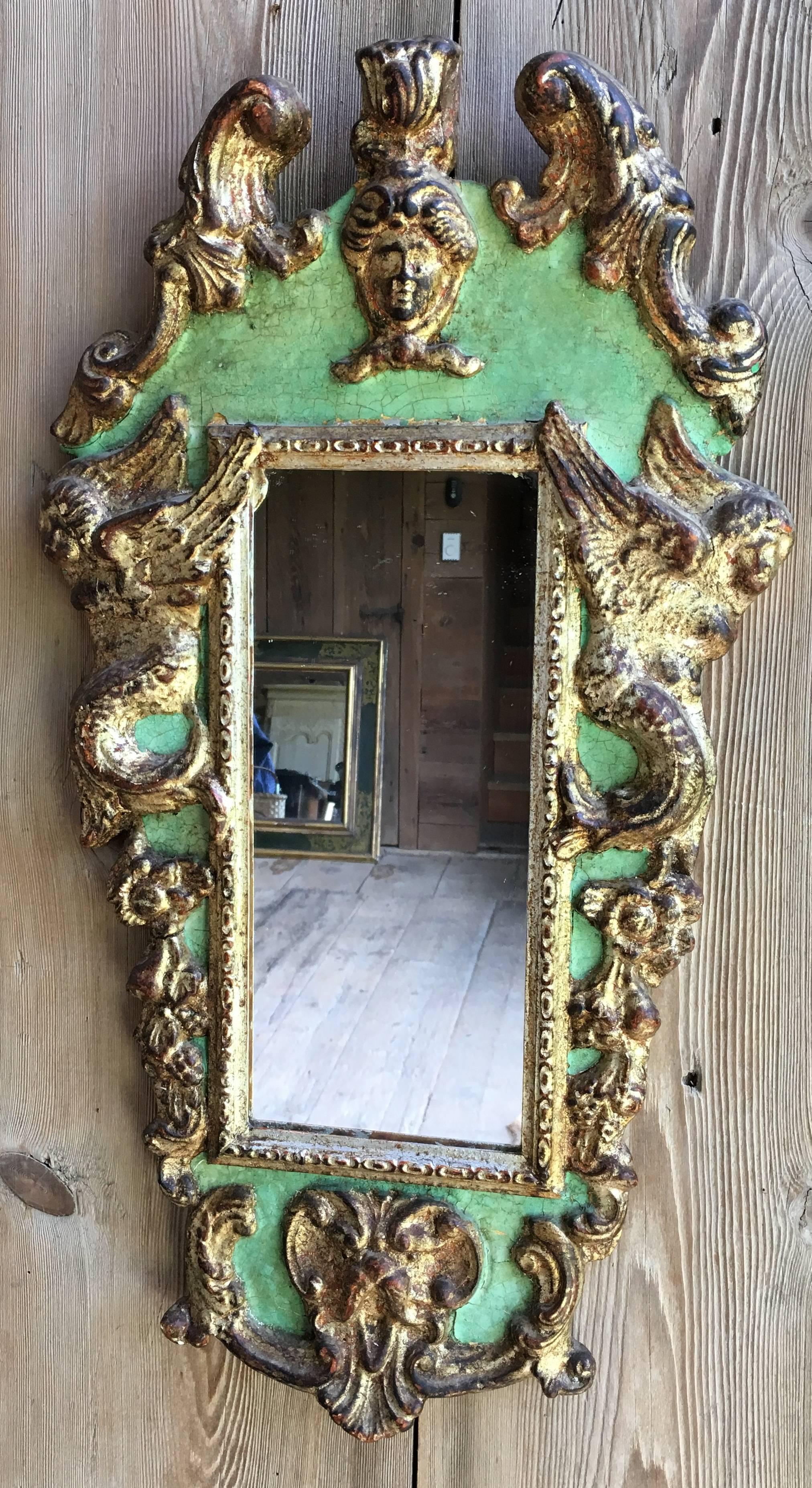 A decorative pair of Italian Baroque style mirrors in green painted finish and parcel-gilt decoration, possibly 20th century. Carved with cherubs and garlands.