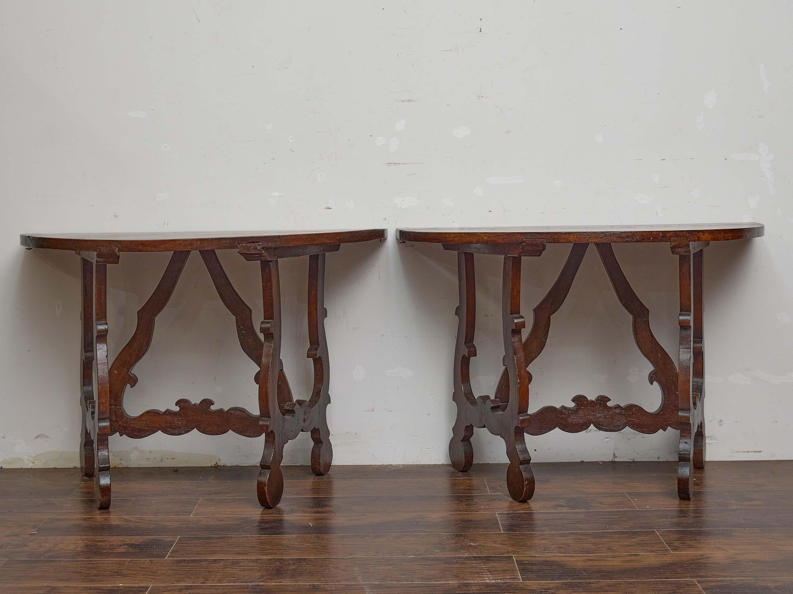 Dieses ausdrucksstarke Paar italienischer Demi-Lune-Konsolentische aus der Zeit um 1800 spiegelt mit seiner kühnen Silhouette und dem skulpturalen Sockel den ornamentalen Schwung des Barockstils wider. Jeder Tisch ist aus reichem Nussbaumholz