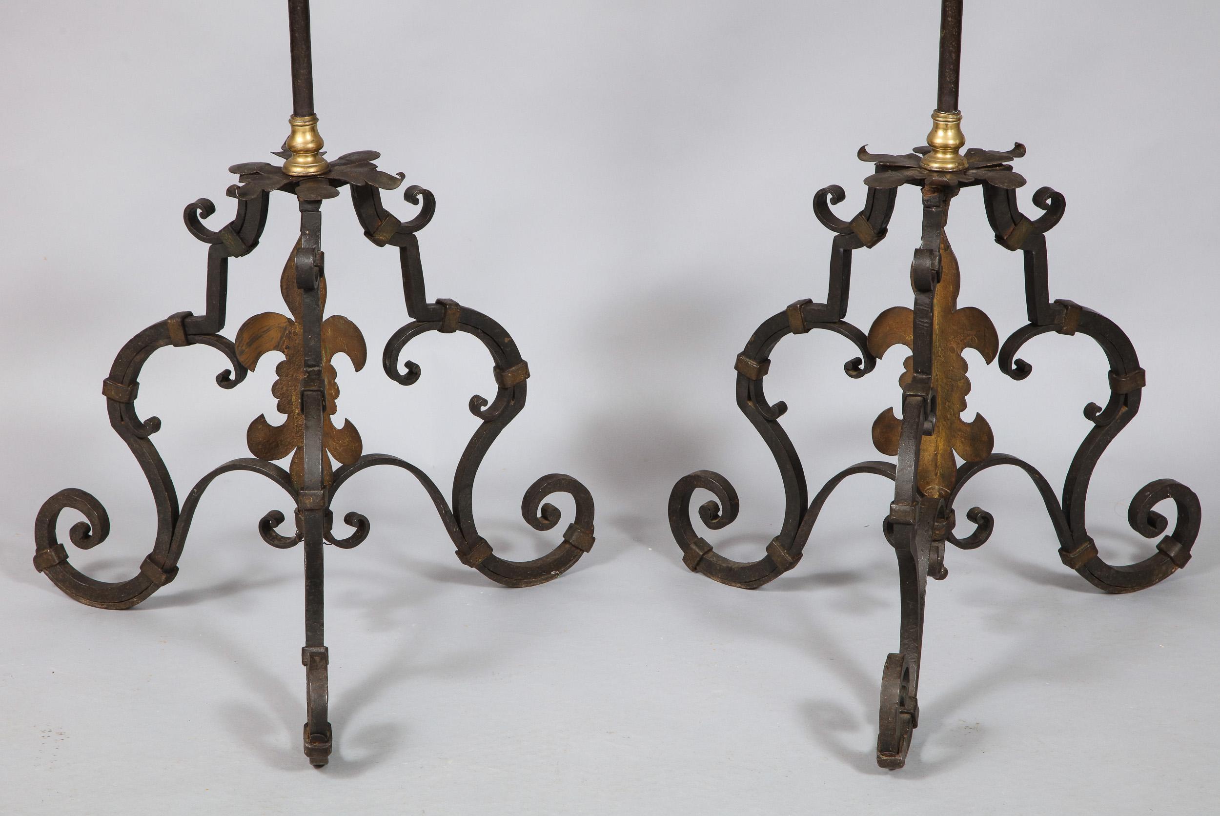 Fine pair of 17th century Italian wrought iron torcheres with bronze turned collars and gilt iron foliate decorations, the candle cups supported by open worked leaves over simple shaft having balustrade turned collars, the bases with scrolled