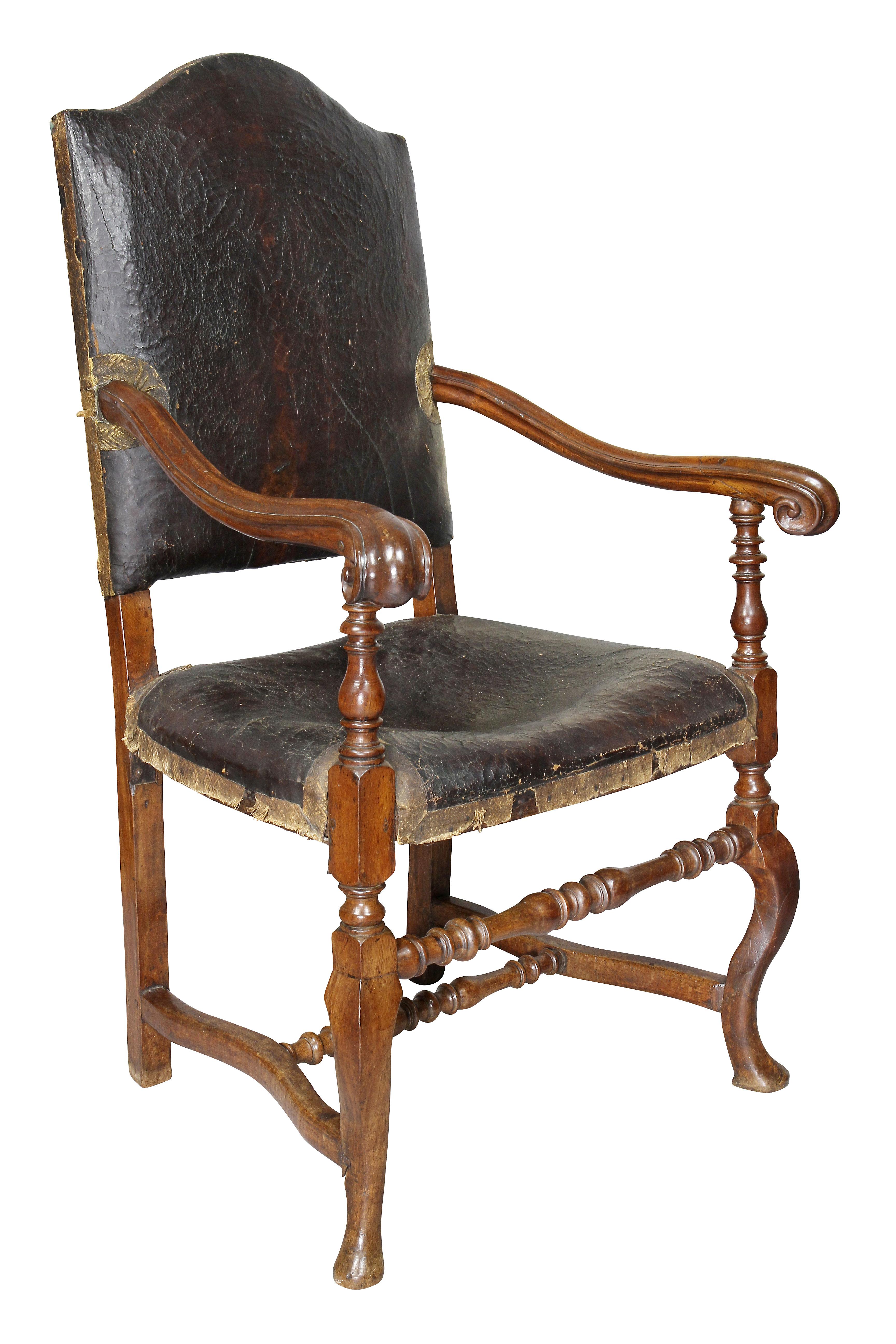 Each with an arched back with original leather, one chair the leather is distressed, carved arms and leather seats raised on slight cabriole legs joined by turned stretchers and pad feet. Provenance; Harvard Art Museum. Generous proportions and
