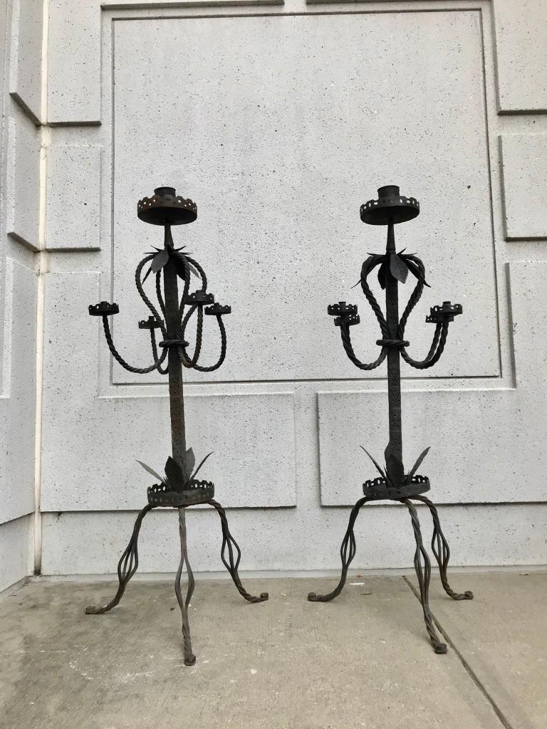 An unusual and gutsy pair of 19th century Italian Baroque style wrought iron torcheres or candelabra. With braided iron arms and legs, hand cut iron leaves and punch decorated shaft. This pair looks almost alive! The workmanship is truly