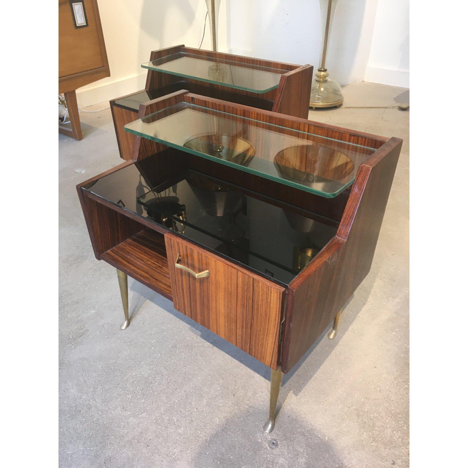 Pair of Italian bedside cabinets comprised of rosewood, brass, black glass tops and transparent glass shelves.
Brass fluted legs.
Italy, circa 1960s.
Minor damages on one cabinet in the area around the glass shelf (as shown in photos).