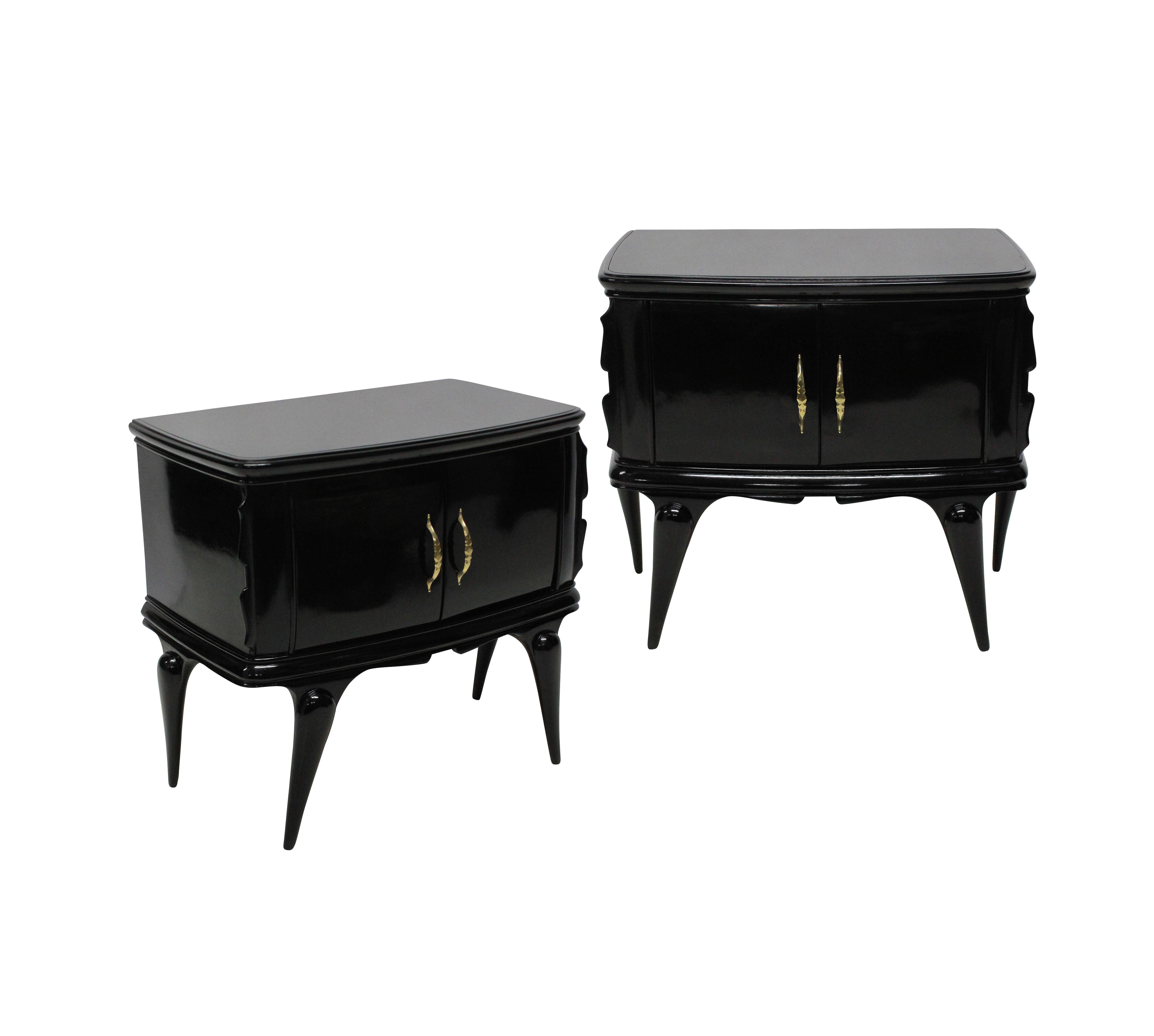 A pair of stylish Italian midcentury nightstands in ebonized wood with charcoal grey glass tops. Each with a central cupboard and two doors.