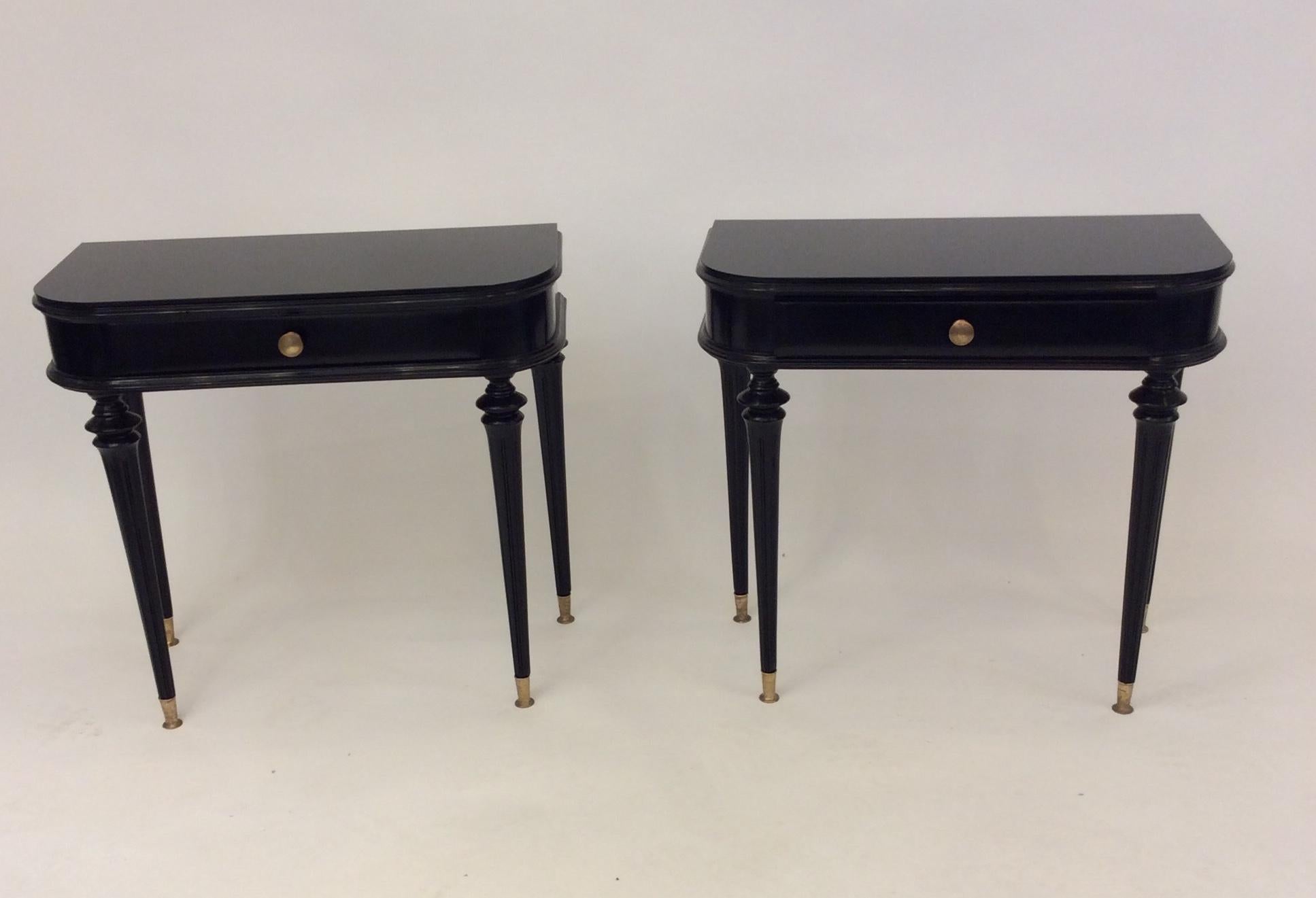 A pair of Italian side tables/nightstands in black lacquer over wood, glass top, each with a drawer with brass hardware and brass shoes on the legs
attributed to Paola Buffa, circa late 1940s.
