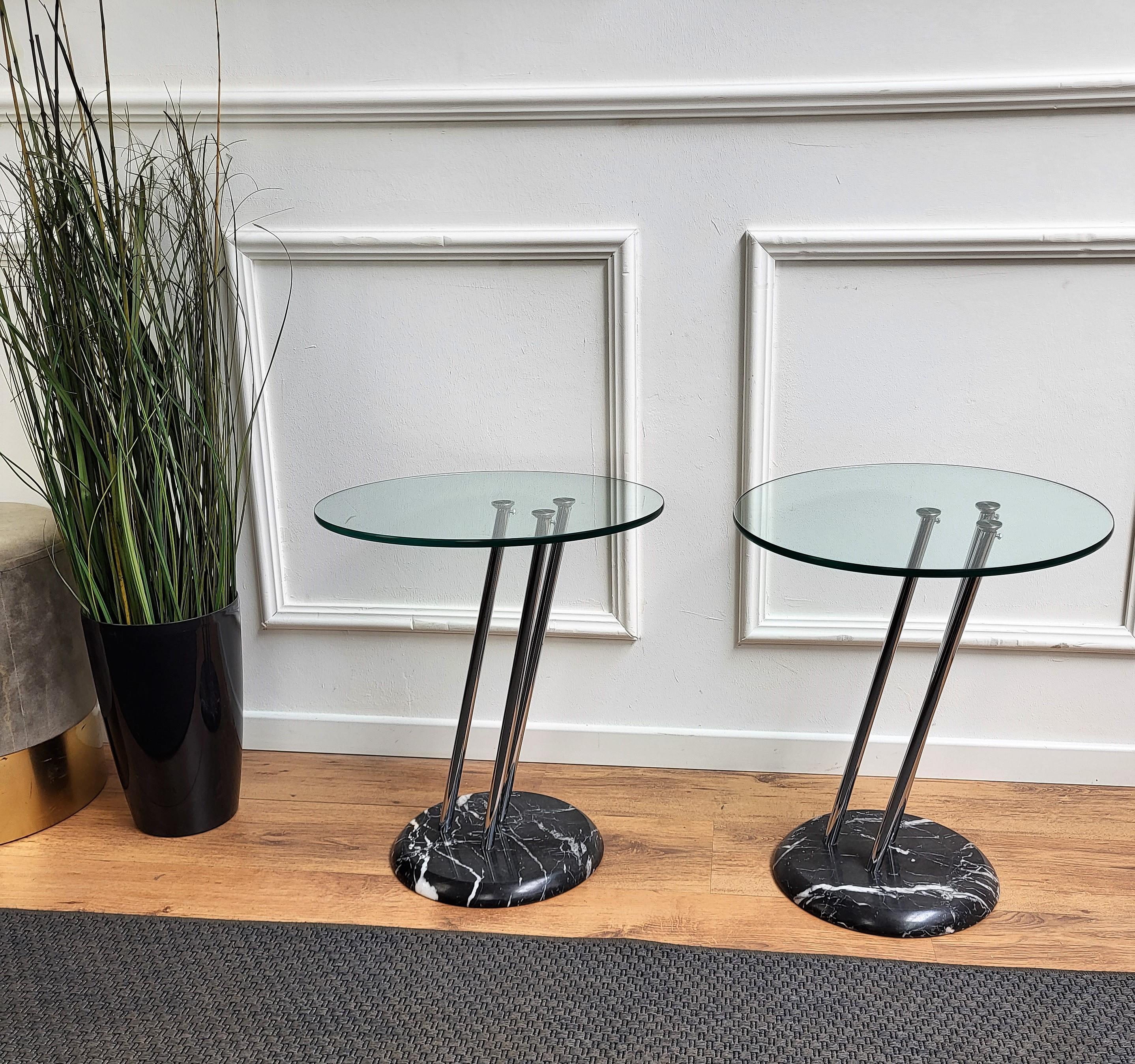 Paire de tables de chevet ou de tables de nuit italiennes très élégantes et raffinées, avec une belle base en marbre noir, trois lignes de structure en métal soutenant le plateau circulaire en verre. Ces tables d'appoint ou ces tables de chevet