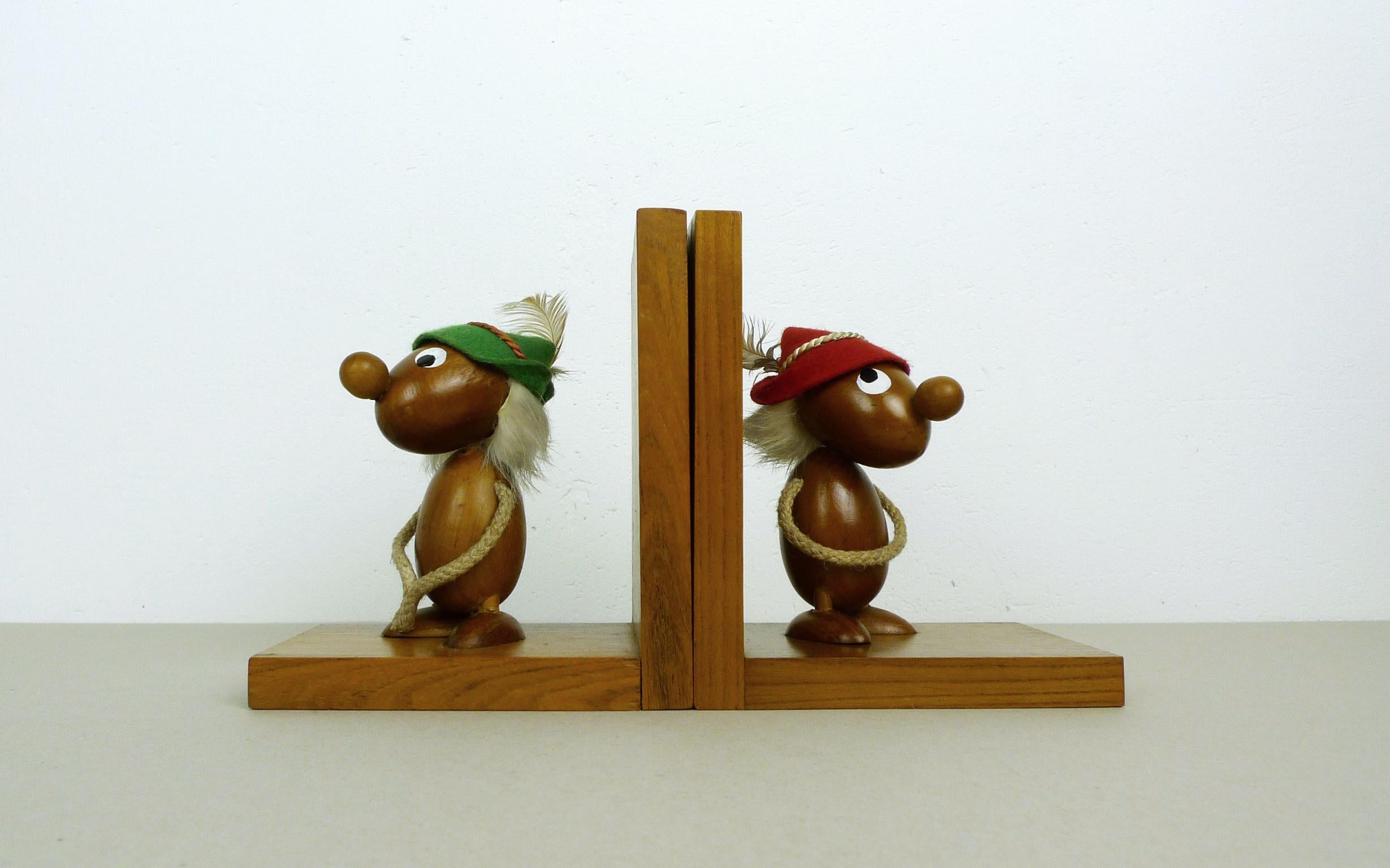 This pair of Italian bookends was produced by Ciola in the 1950s. They feature teak figurines with red and green hats made of felt. The beige-colored arms are made of twisted cord. The bookends are in good original condition.