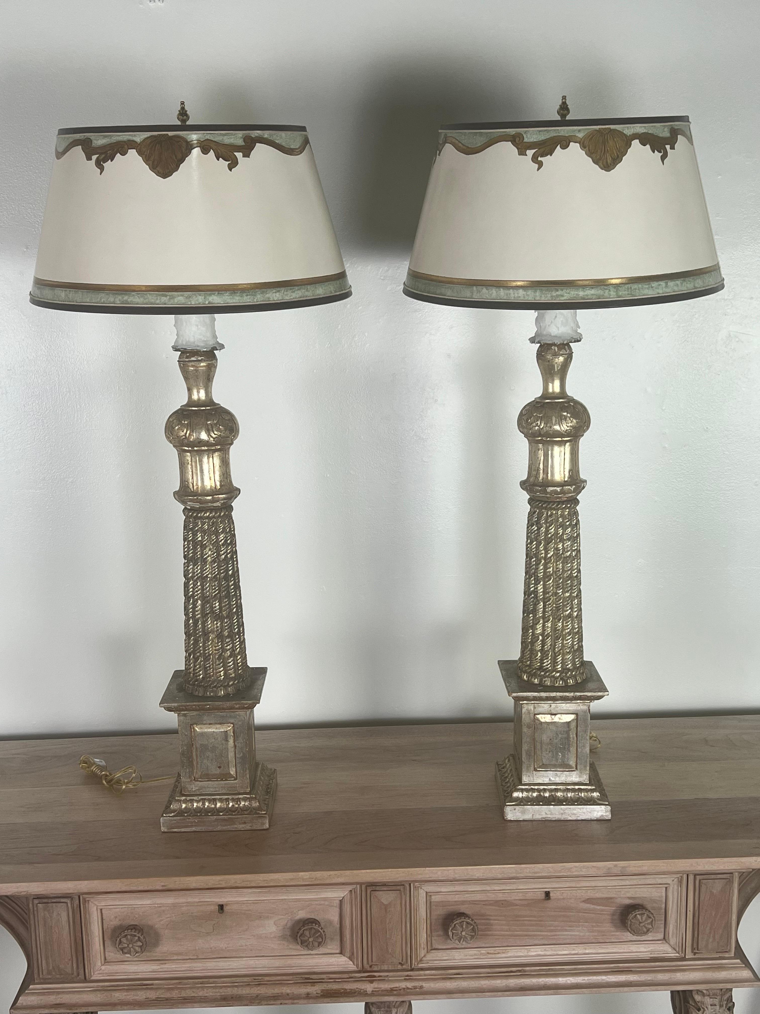 Pair of Monumental size beautifully carved Italian Neoclassical style silvered lamps. The lamps have custom hand painted parchment shades. The lamps are newly wired with drip wax candle covers. They are ready to use.
