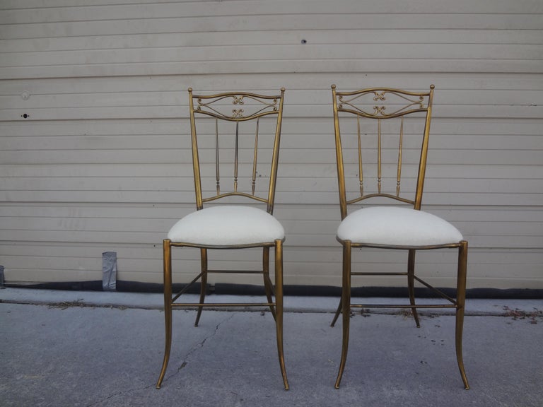 Pair of Italian brass Chiavari chairs.
These unusual brass Chiavari chairs retain their beautiful original patina and can be polished if desired. This great pair of Italian brass side chairs have been newly upholstered in cream mohair fabric.