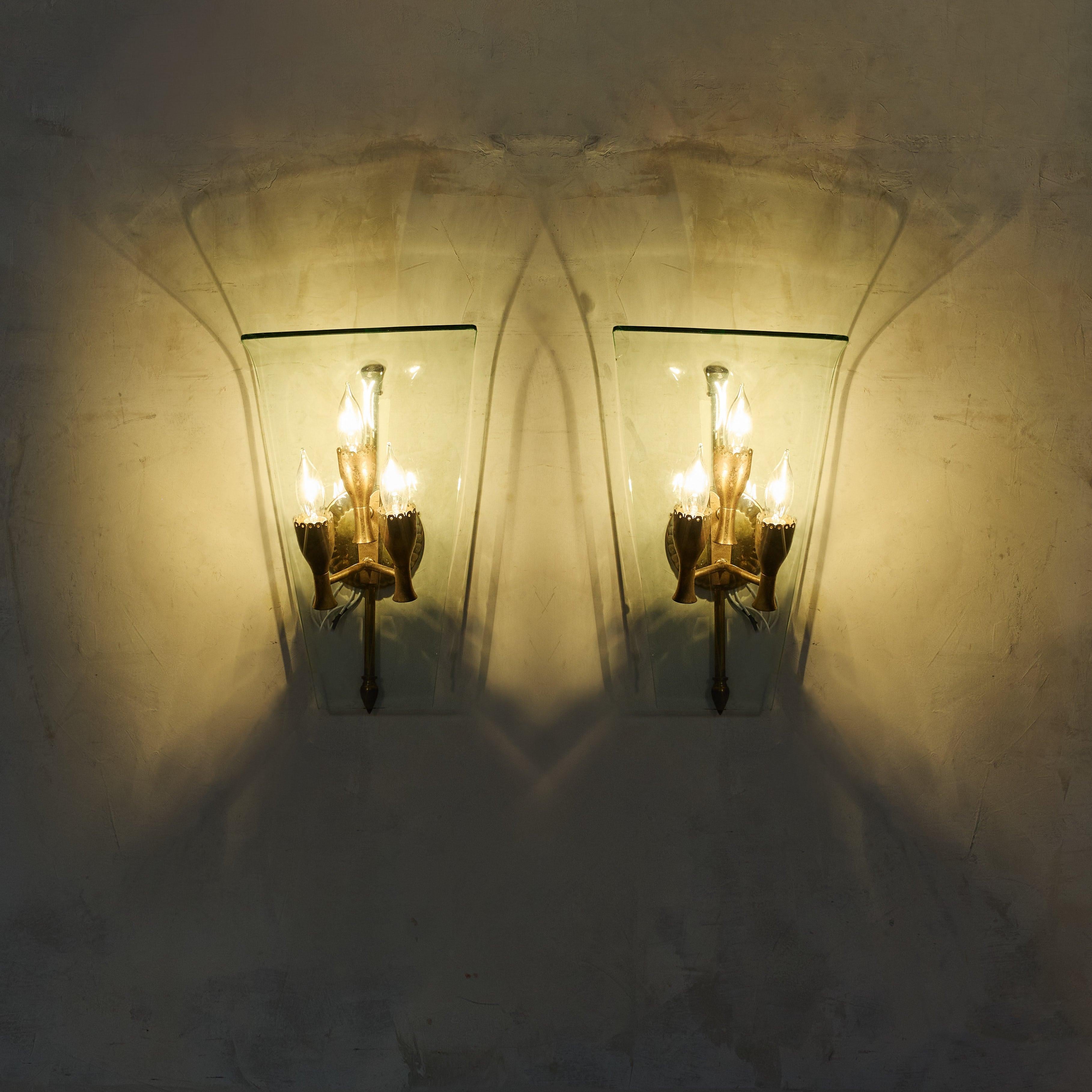Attribuita a Fontana Arte, questa squisita coppia di appliques italiane risale agli anni Quaranta. Ciascuna applique presenta un paralume in vetro graziosamente curvo, che incornicia un trio di prese a candela in ottone patinato con bobeches