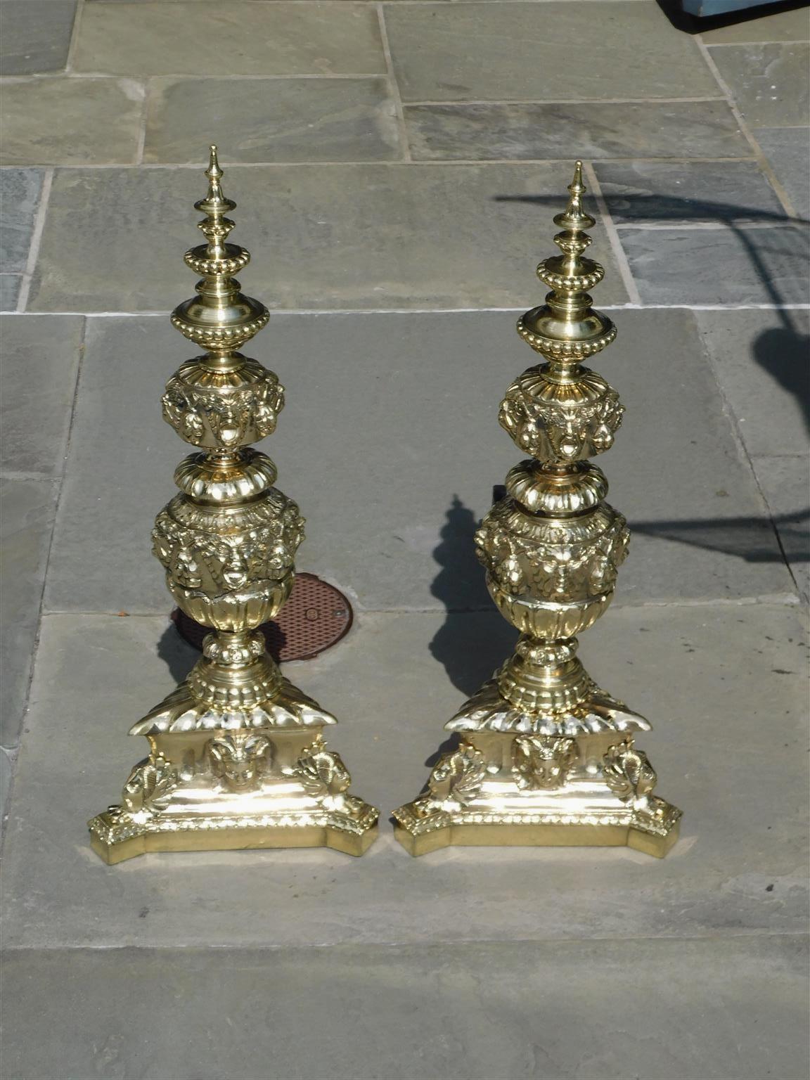 Pair of Italian brass neoclassical figural tiered beaded urn finial andirons resting on decorative fluted triangular bases, Early 19th Century.