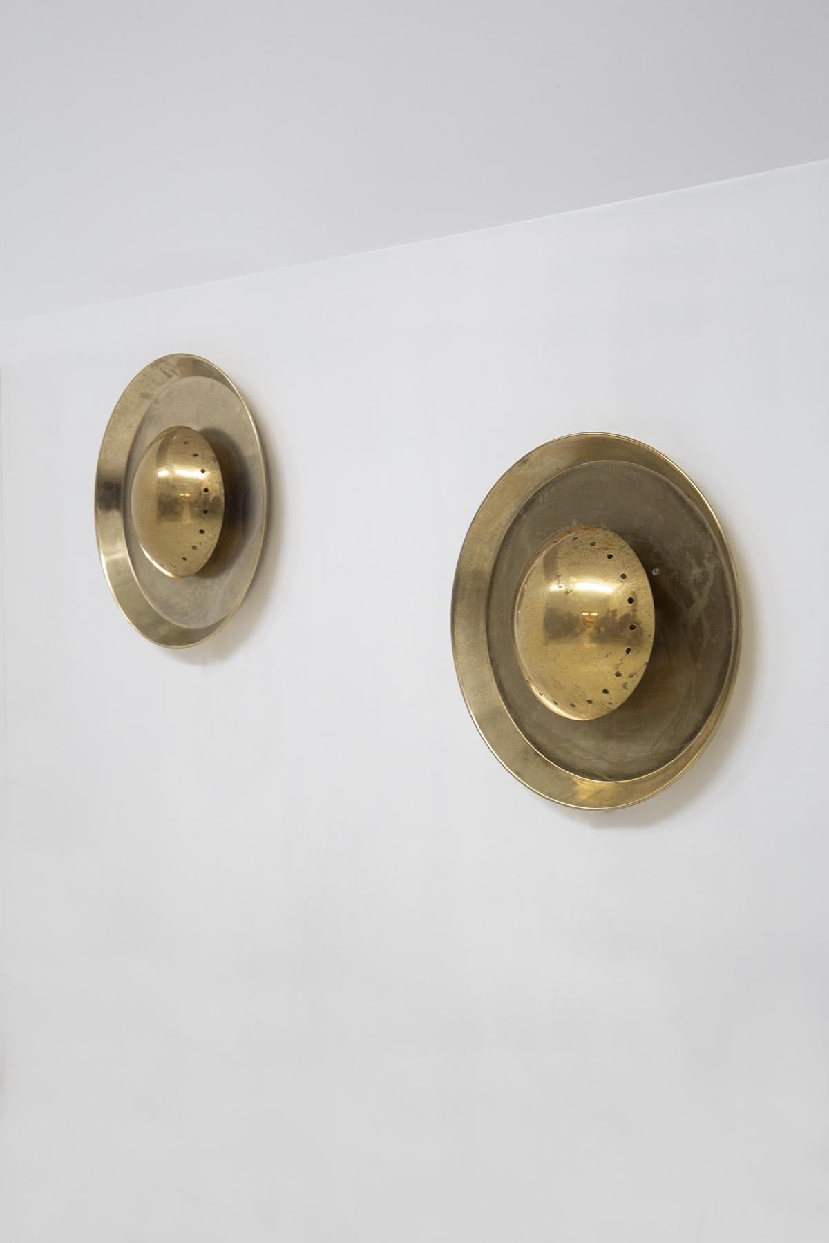 Pair of brass lamps designed and produced in the 20th century, of fine Italian manufacture. The wall lamps are made entirely of brass and have a circular shape. It is a geometric play, because inside the circle there are two other circles, a larger
