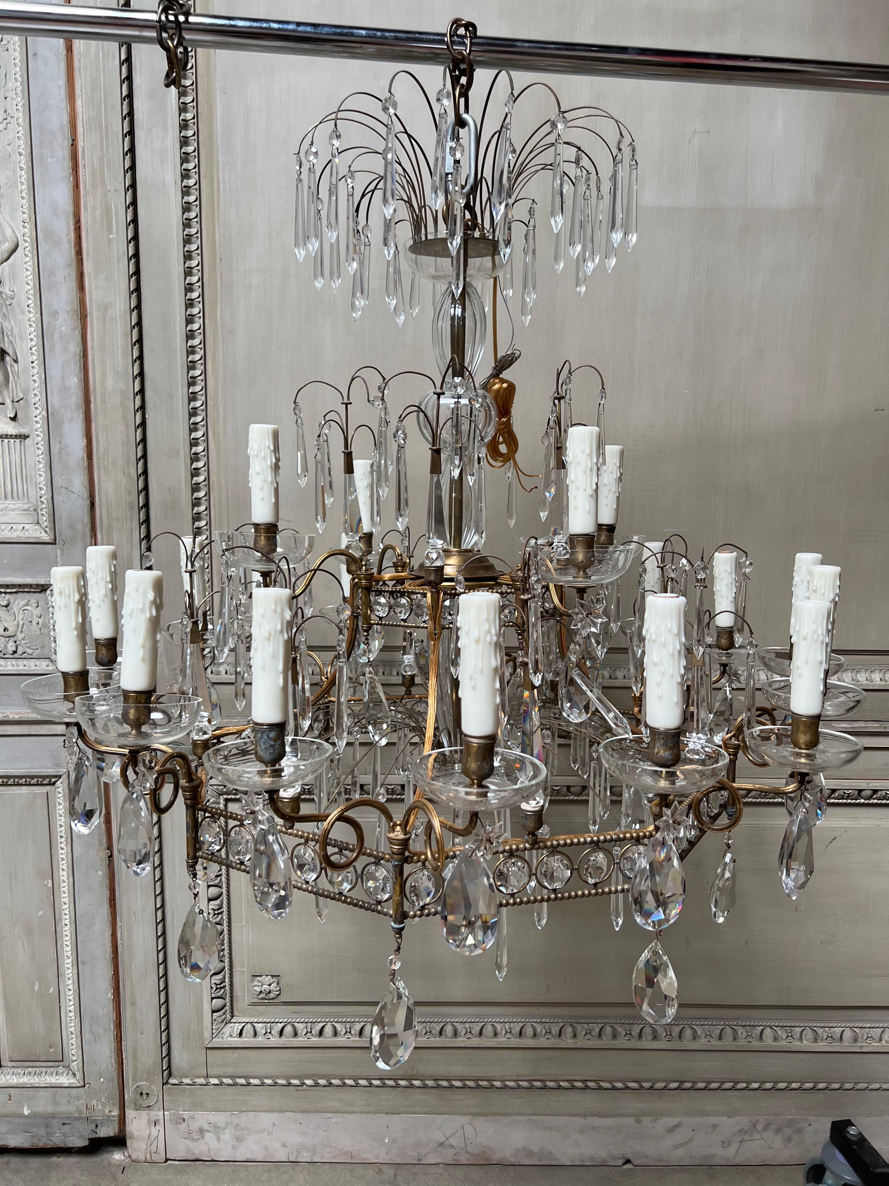 A large pair of Italian bronze and crystal chandeliers from the 1920's in the neoclassical-art deco style. These chandeliers are twenty lights each and are a beautiful, glamorous style. They are perfect for a large room.