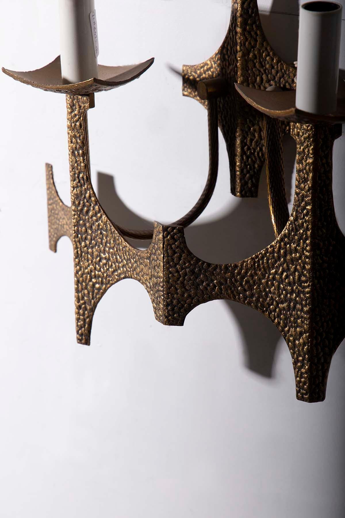 Imagine a pair of wall lamps that transport you back in time to the fascinating era of Italian Brutalism. These exquisite design pieces are made of brass, meticulously hammered by expert hands to achieve a deliberately rough appearance. Each lamp