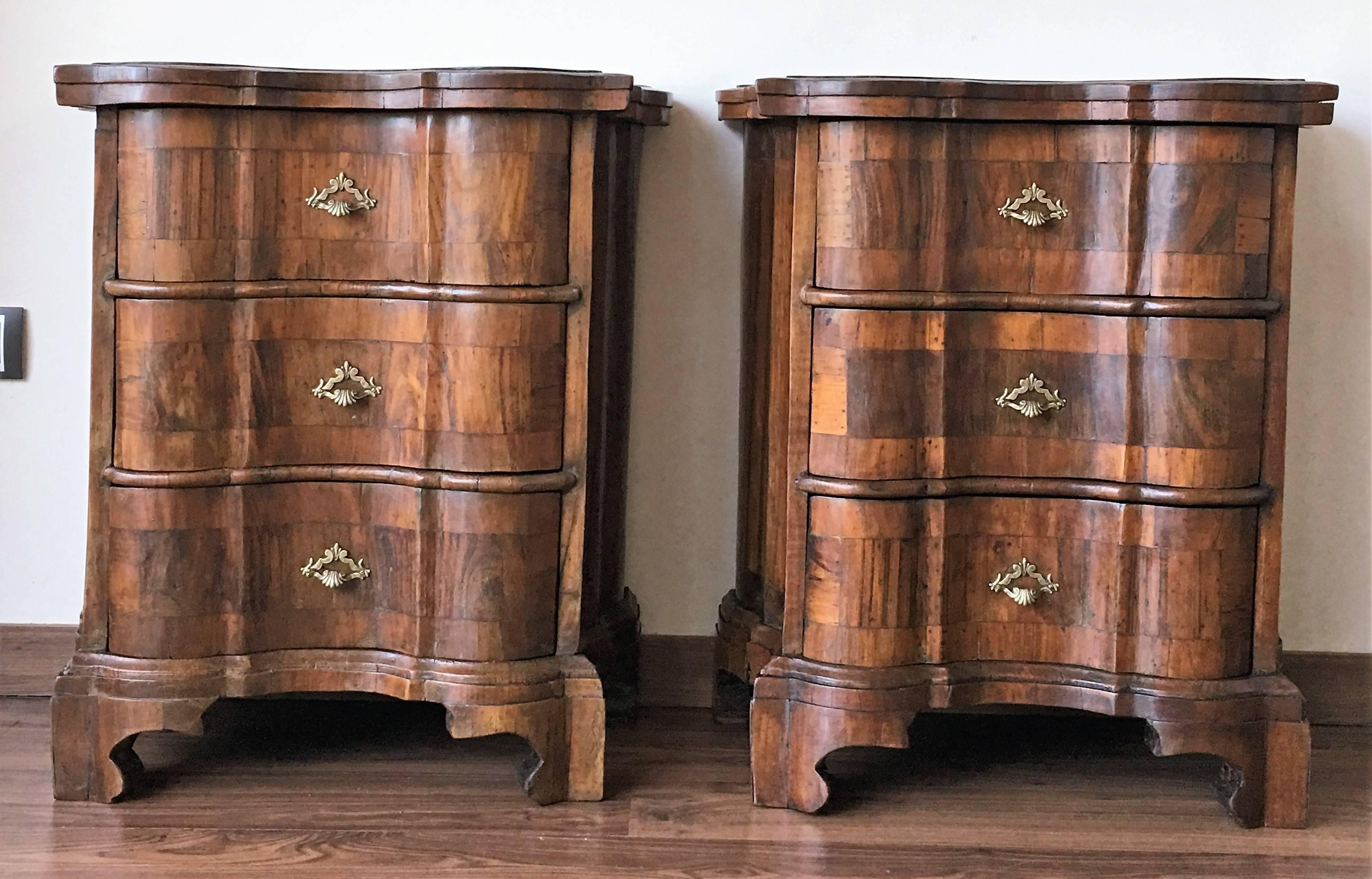 Having butterfly form tops and drawers with rounded corners and molded edges above conforming cases housing three drawers, the drawers intricately veneered with various tones of burl walnut and cherrywood, retaining antique hardware, having shaped