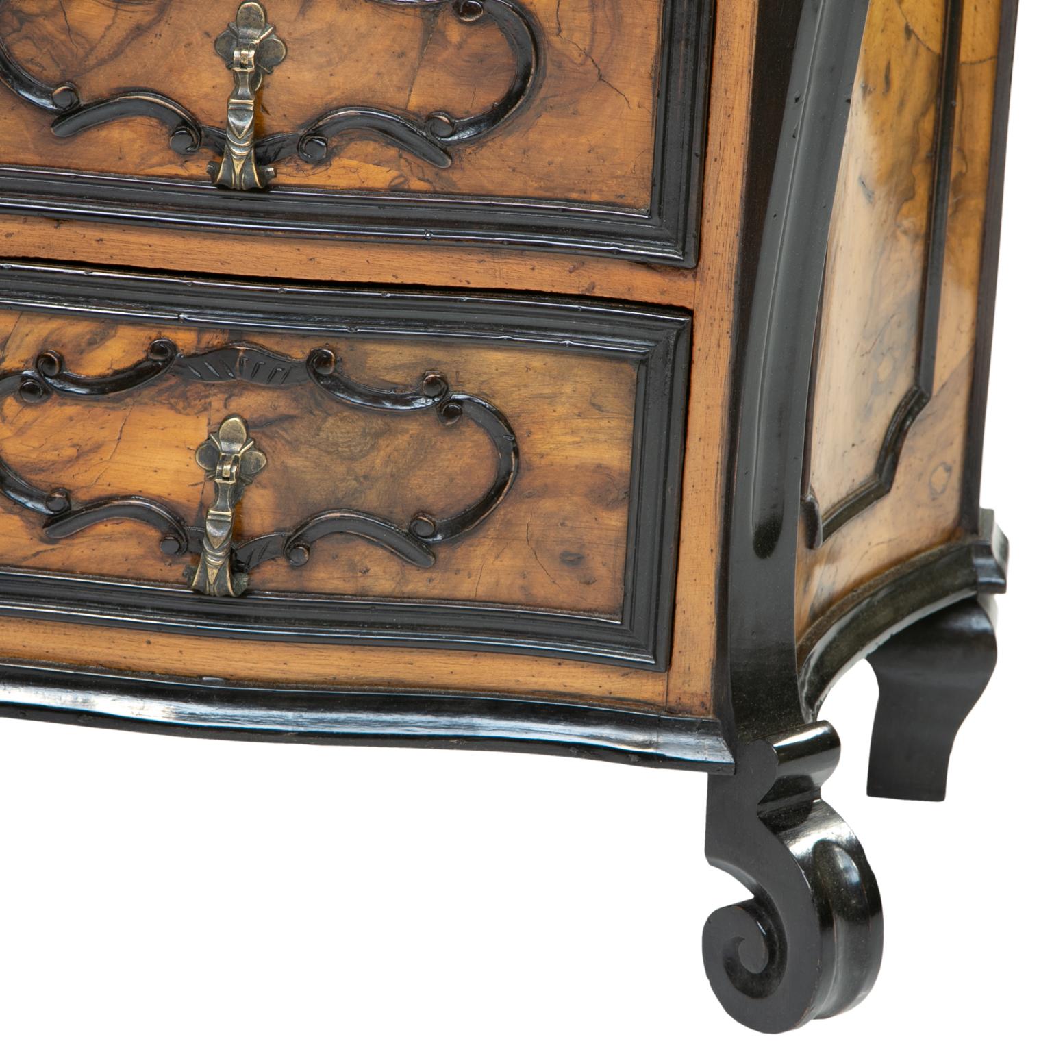 A pair of burl wood side chest of drawers. These chests are petite in size. The chests are quality reproductions made from old wood and in the style of furniture from Milan. They have ebonized wood accents and burl olive wood patched veneer. A