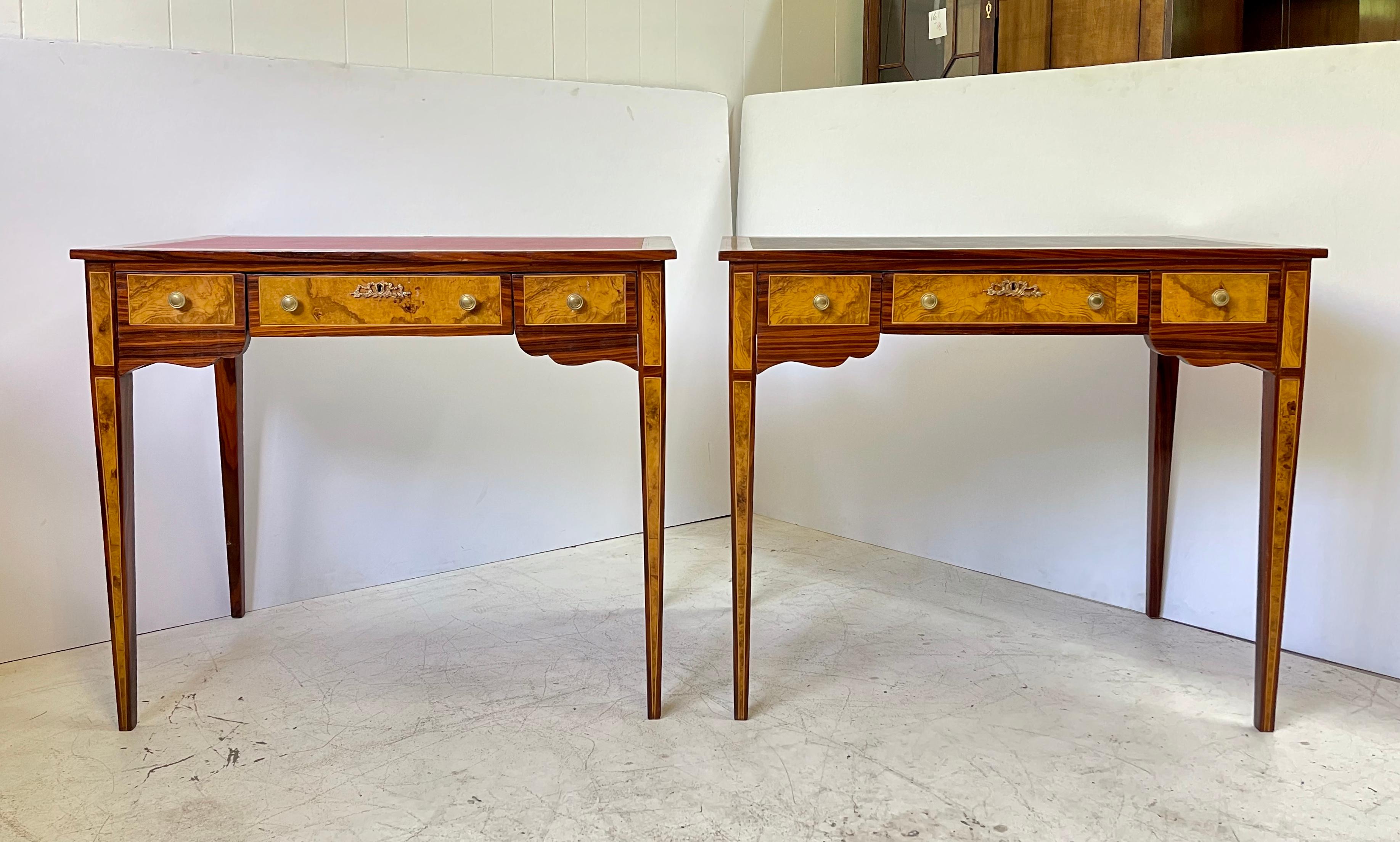 Fabulous and intricate pair of 20th century neoclassical writing desks or side tables styled in burl wood veneers and string inlays. Each has a tooled and inset leather top over a frieze holding three drawers with brass knobs and a scalloped apron.