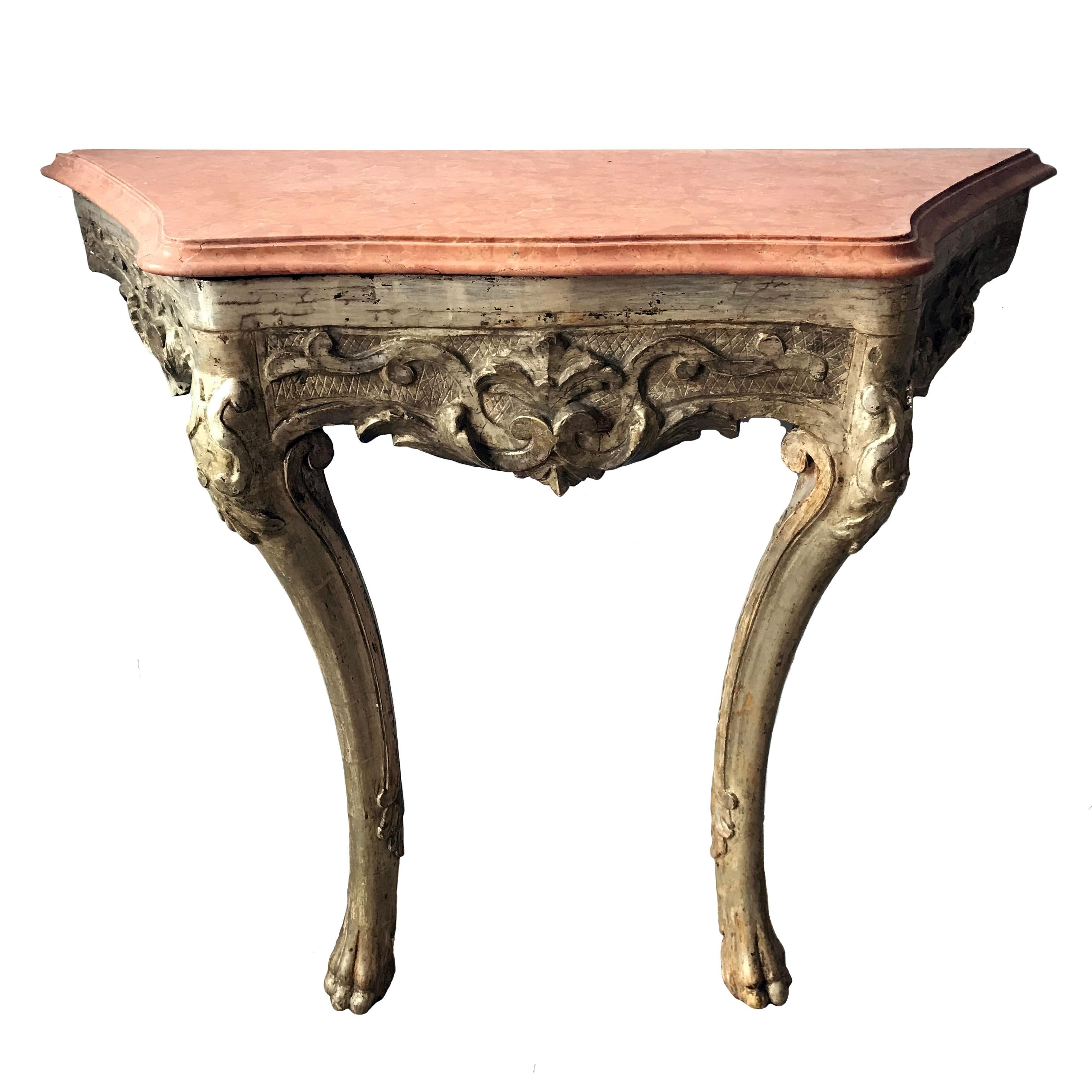 A stunning pair of Italian late C18th silvered carved wood console tables. The later Violet de Brignoles marble tops have a soft moulded edge sitting above a bolding carved apron of flowing acanthus leaves and C-scrolls on a hatched background. The