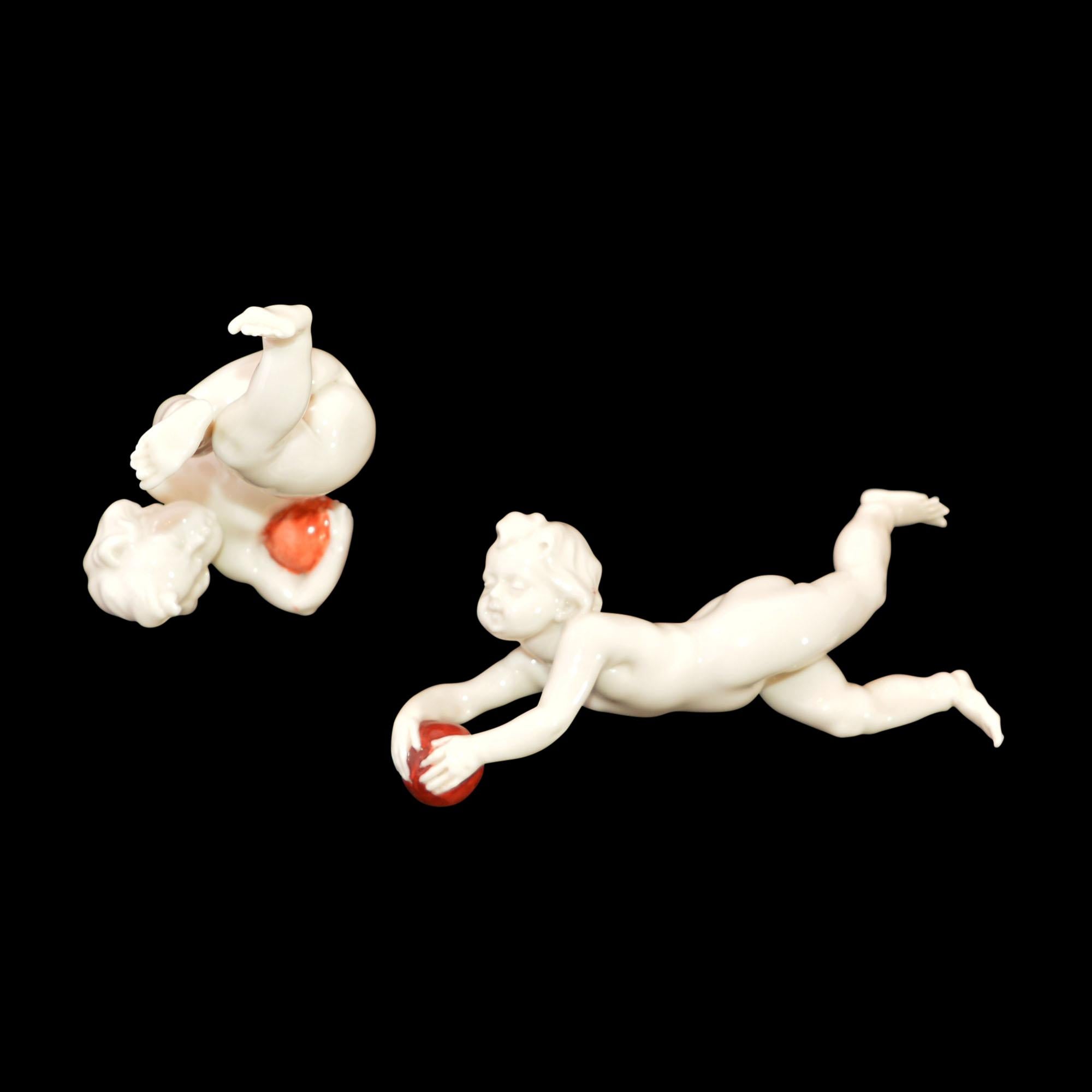 Lovely cream colored porcelain putti in motion will be sure to bring a smile to your face when you see them. One can only imagine what the creator was thinking as he formed the playful two. The balls are painted an orangish red. The longest one
