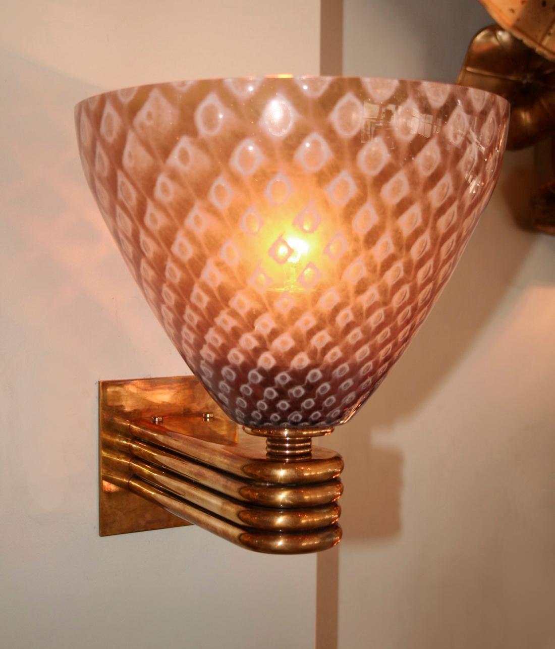 Exotic and moody wall lights with Murano glass conical shades in a 'caramel' pattern held by fluted brass arms.