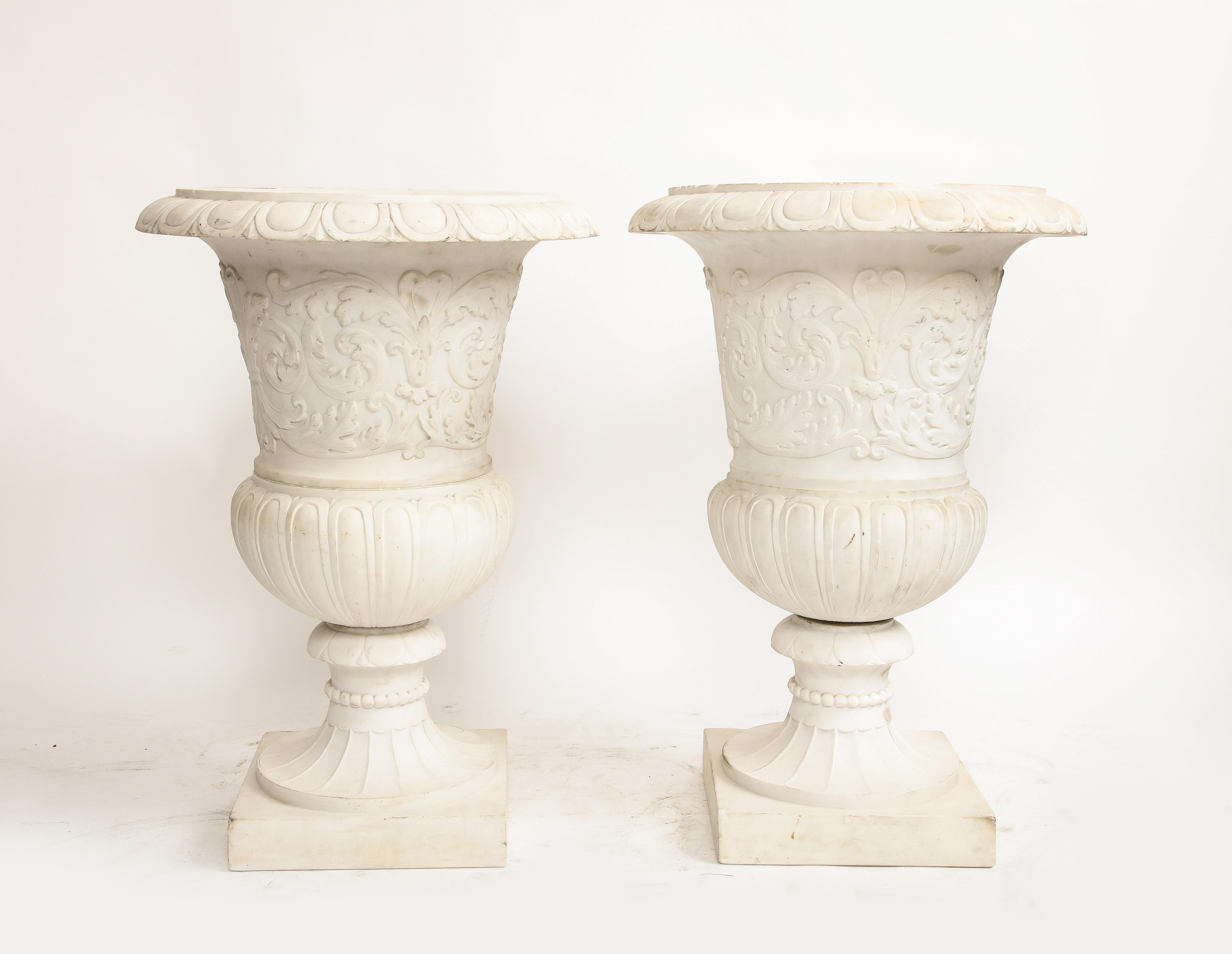 Magnifique paire de vases Médicis italiens en marbre de Carrare avec des motifs néoclassiques en relief.  D'une hauteur impressionnante de 30 pouces, ces vases témoignent de l'art impeccable inhérent au marbre de Carrare.
D'une facture élaborée et