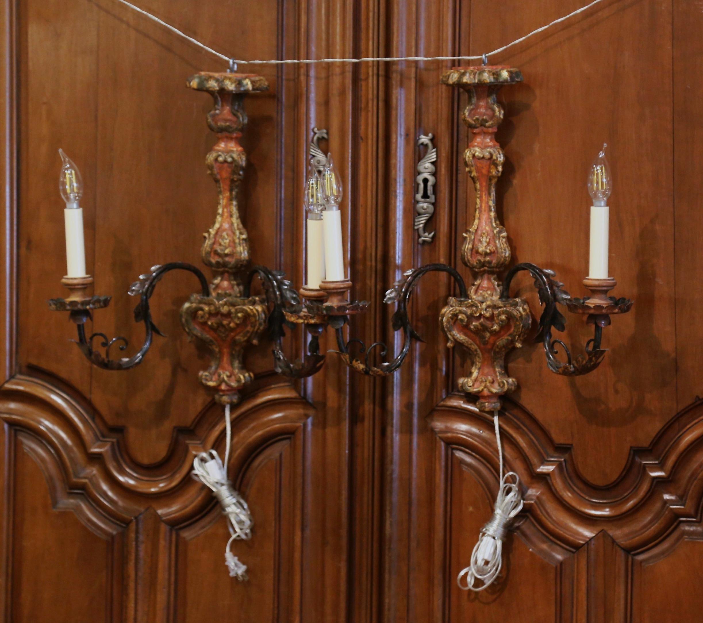 Light up a dining room or powder room with this elegant pair of antique fixtures. Crafted in Italy circa 1980, each sconce features intricate hand-carvings with leaf and scrolled motifs in the Louis XV style; each light has a double metal arm