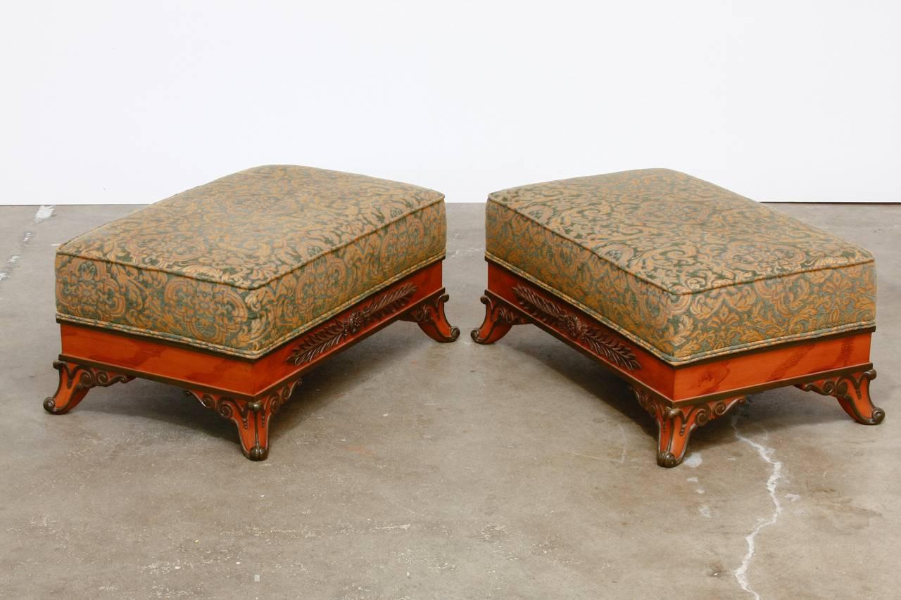 Impressive pair of Italian upholstered ottoman or benches featuring a large carved and painted frame. The seats are upholstered with a tapestry style fabric over deep, thick cushions. The frames are decorated with scrolls and laurel leaf motifs.
