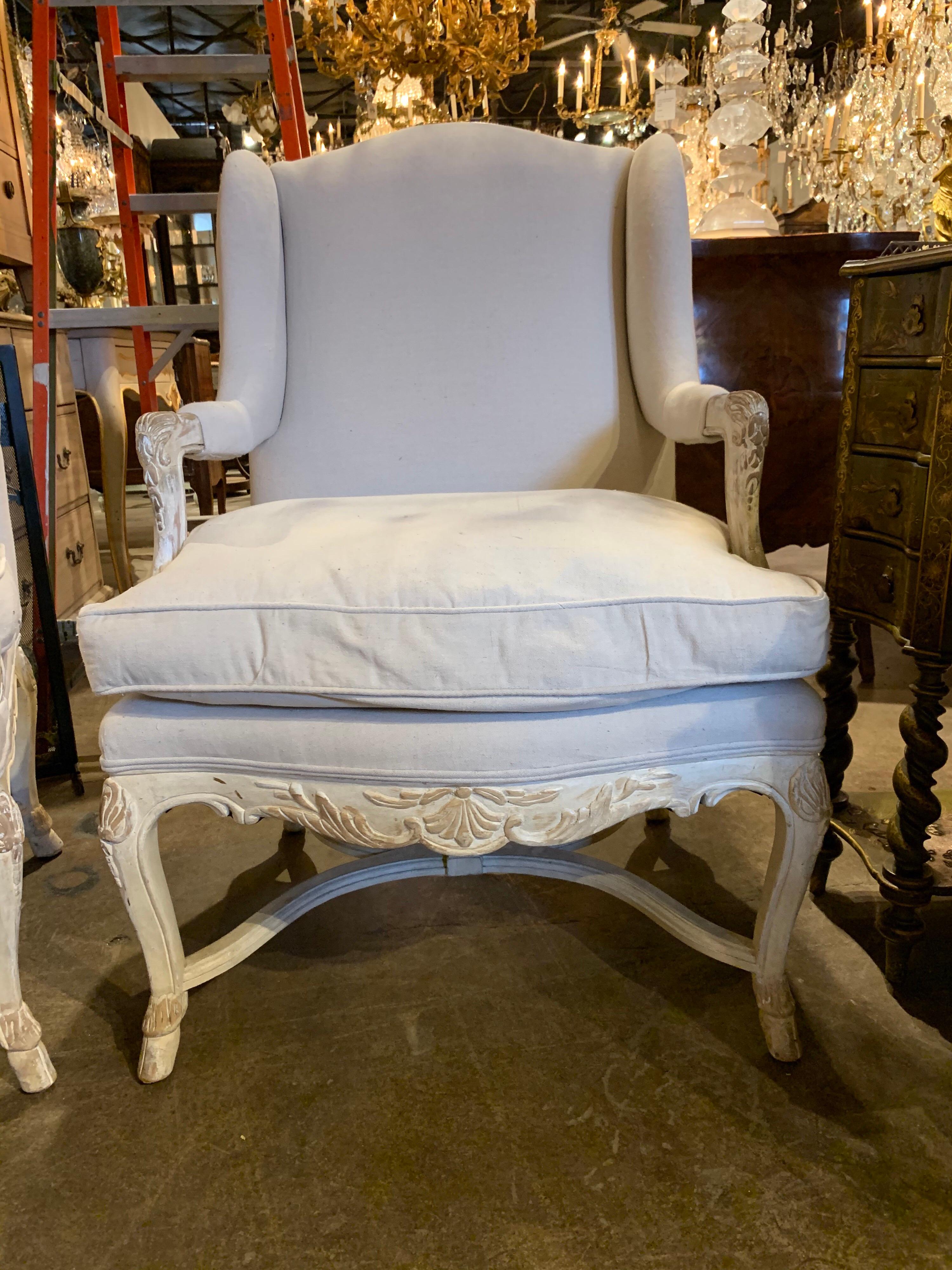 Gorgeous pair of Italian carved and white washed Bergères upholstered in a beige colored linen. These chairs are so pretty and amazingly comfortable too. A fine addition to any home!