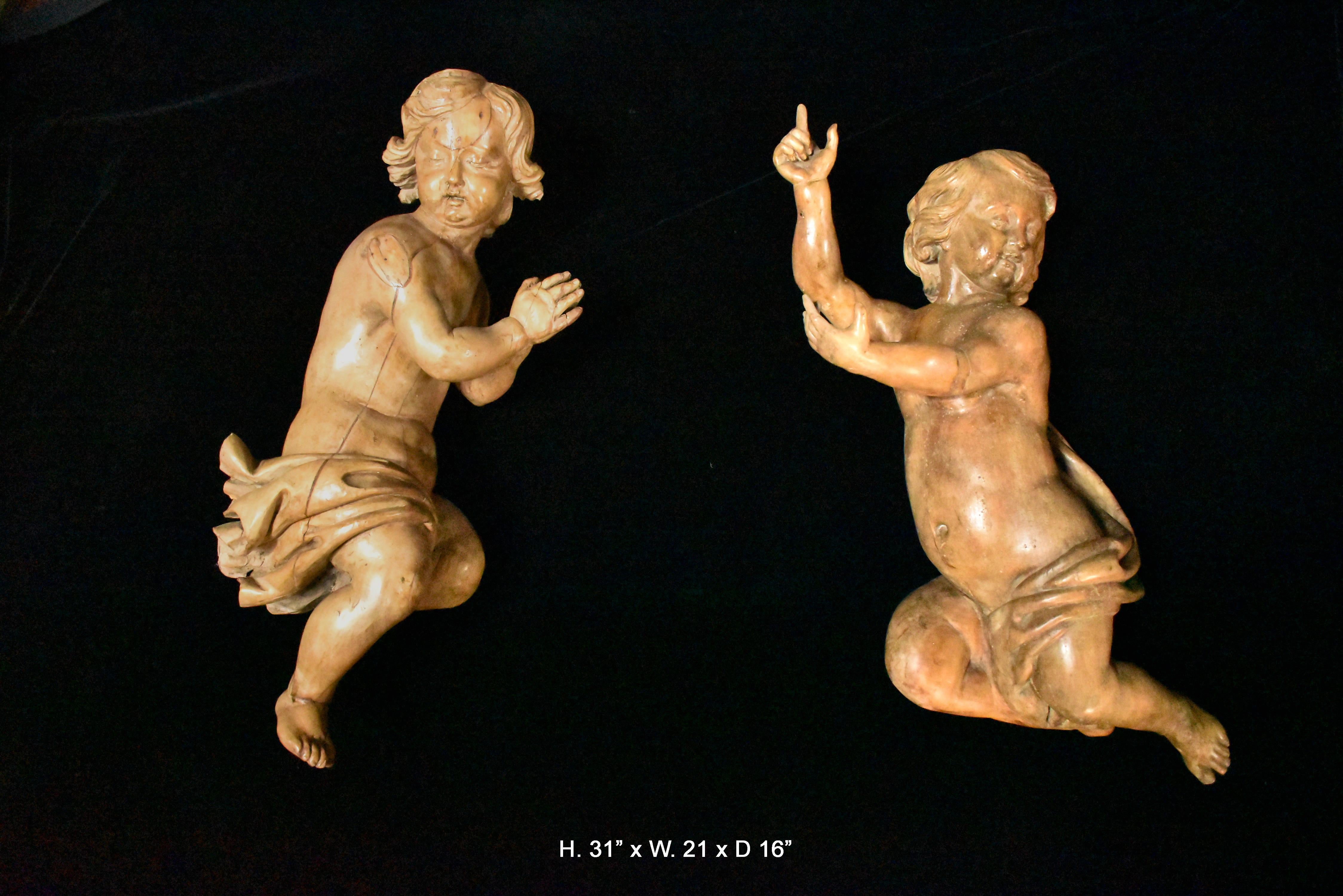 Exquisite large pair of 18th century or possibly 17th century Italian hand carved fruitwood figures of putti with garments. One putto is displaying prayer hands while the other is displaying hand gestures.
Bring your attention to the meticulous