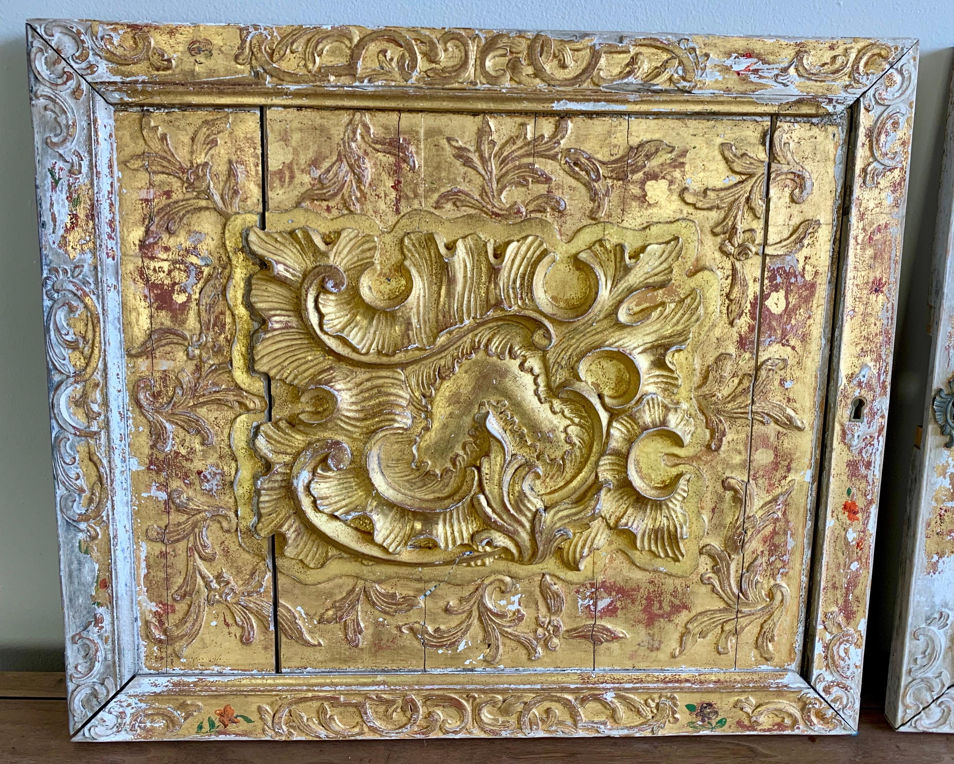 Pair of hand carved giltwood panels that were originally part of a larger piece of furniture. They were cabinet doors as you can still see the key hole cover on one of the panels. These panels could be built into a project or can be hung as unique