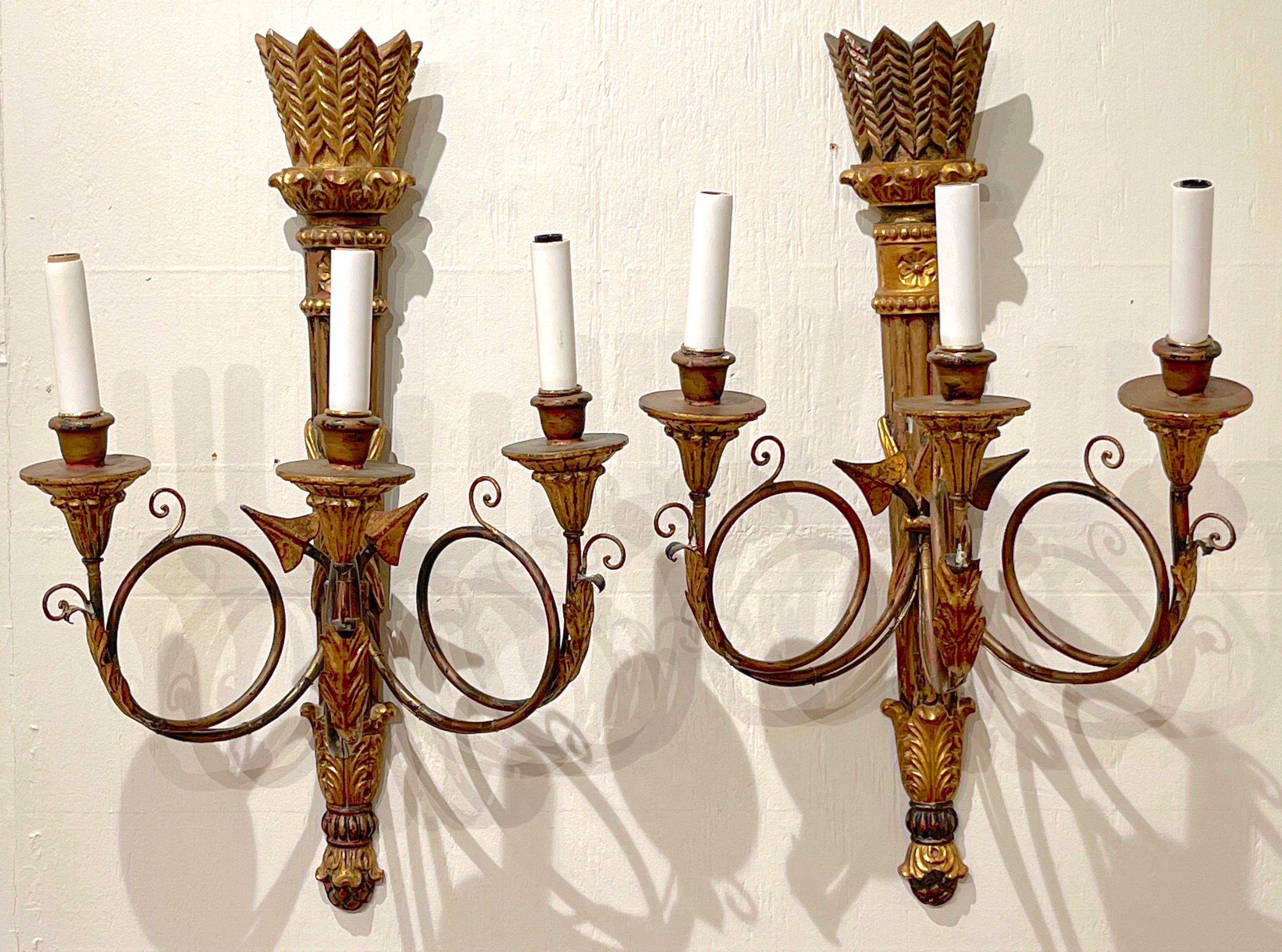 Pair of Italian carved giltwood neoclassical Quiver motif 3-light sconces 
Italy, circa 1950s

Each one of good size, well carved giltwood quiver motif backplates, fitted with three gilt metal arrow motif arms with candelabra lights. New wiring.