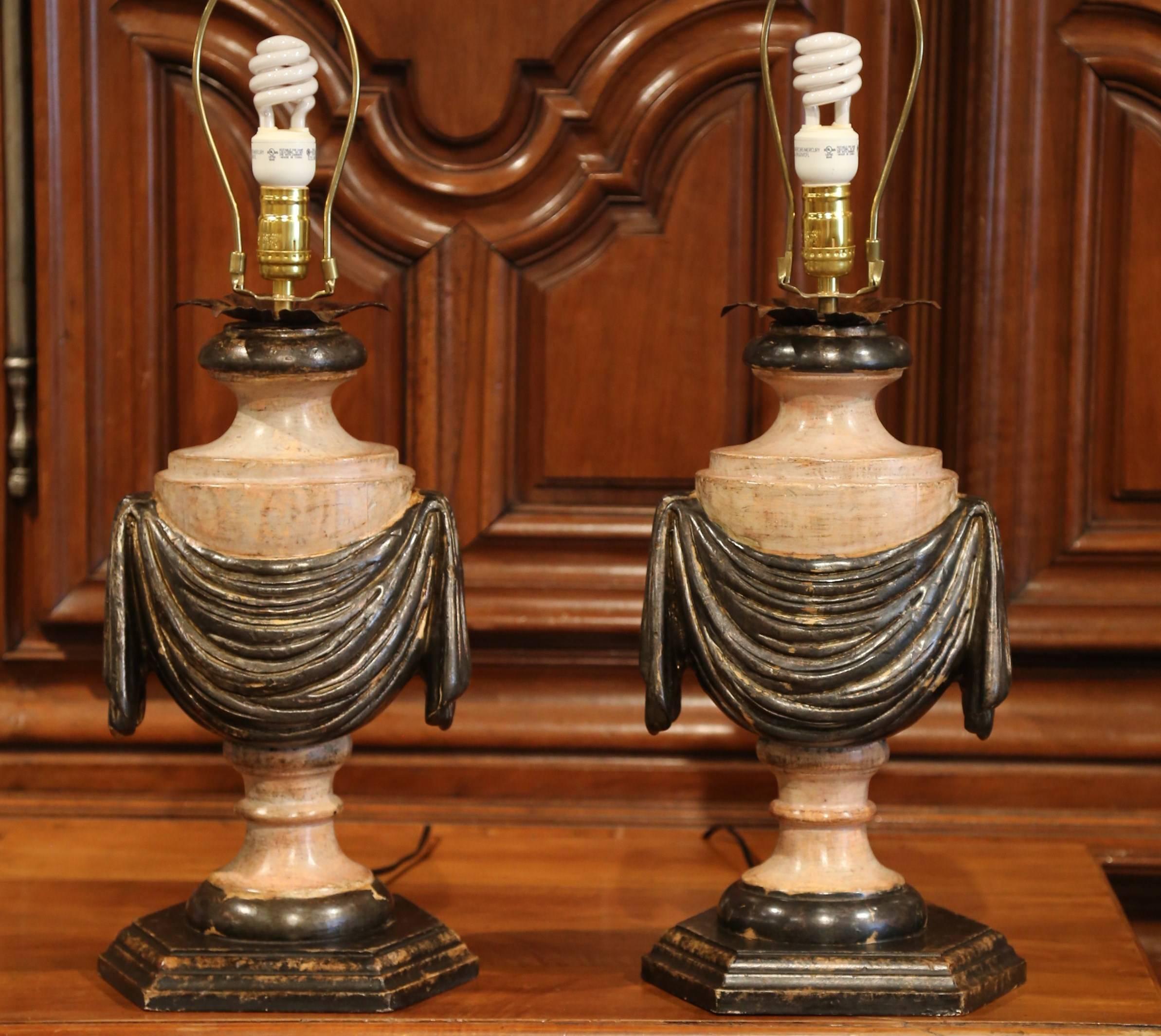 Incorporate extra light into a living room or bedroom with this pair of hand-carved and hand-painted wood lamp bases from Italy. The bases are in the shape of a traditional antique urn with hand-carved swags and sit on a hexagonal base. Both table