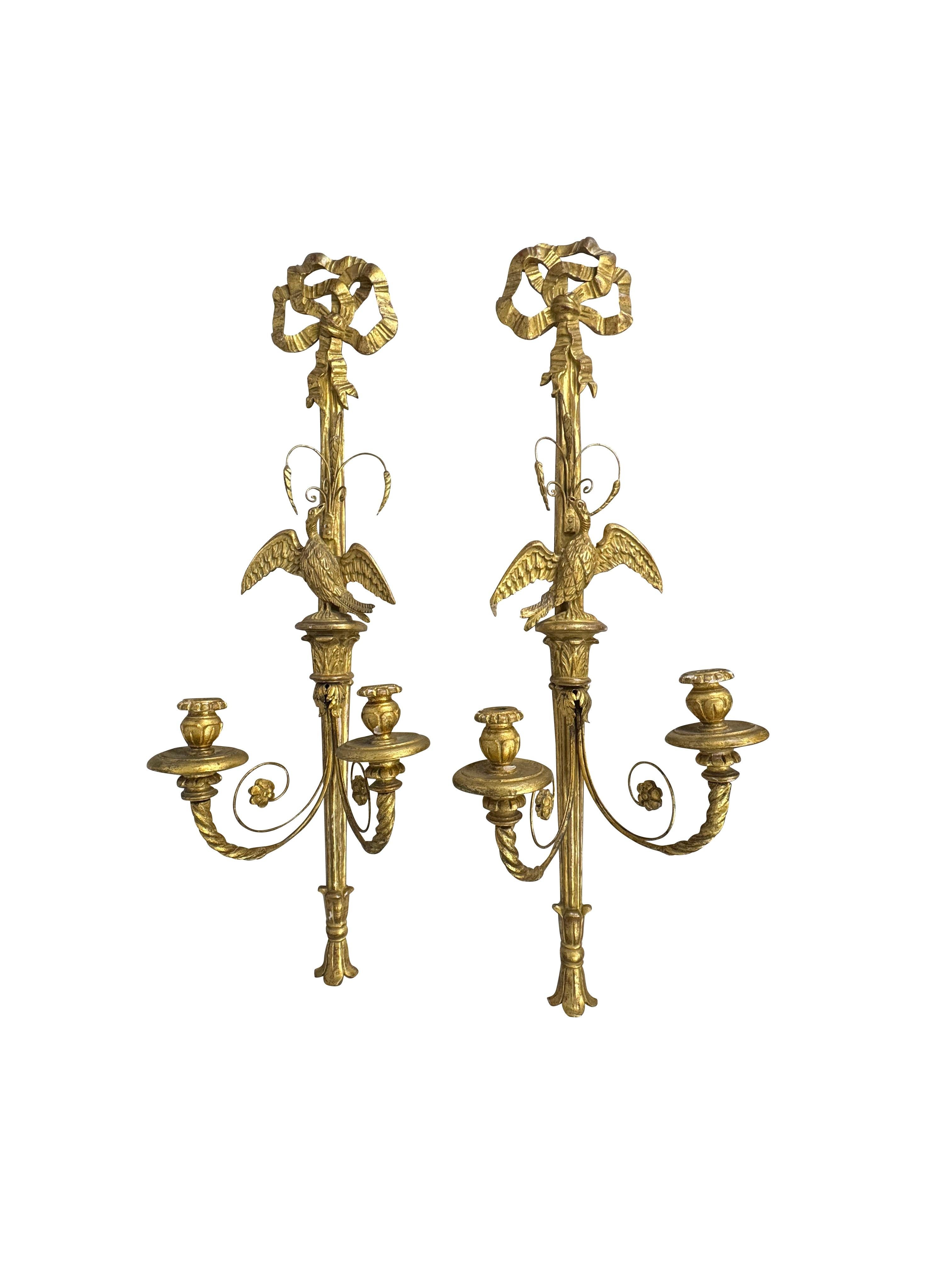 Pareja de candelabros italianos de dos luces tallados y de madera dorada
Finales del siglo XIX a principios del XX
Cada candelabro, finamente tallado, está coronado por una cresta de lazo y cinta sobre un águila estilizada con las alas extendidas,