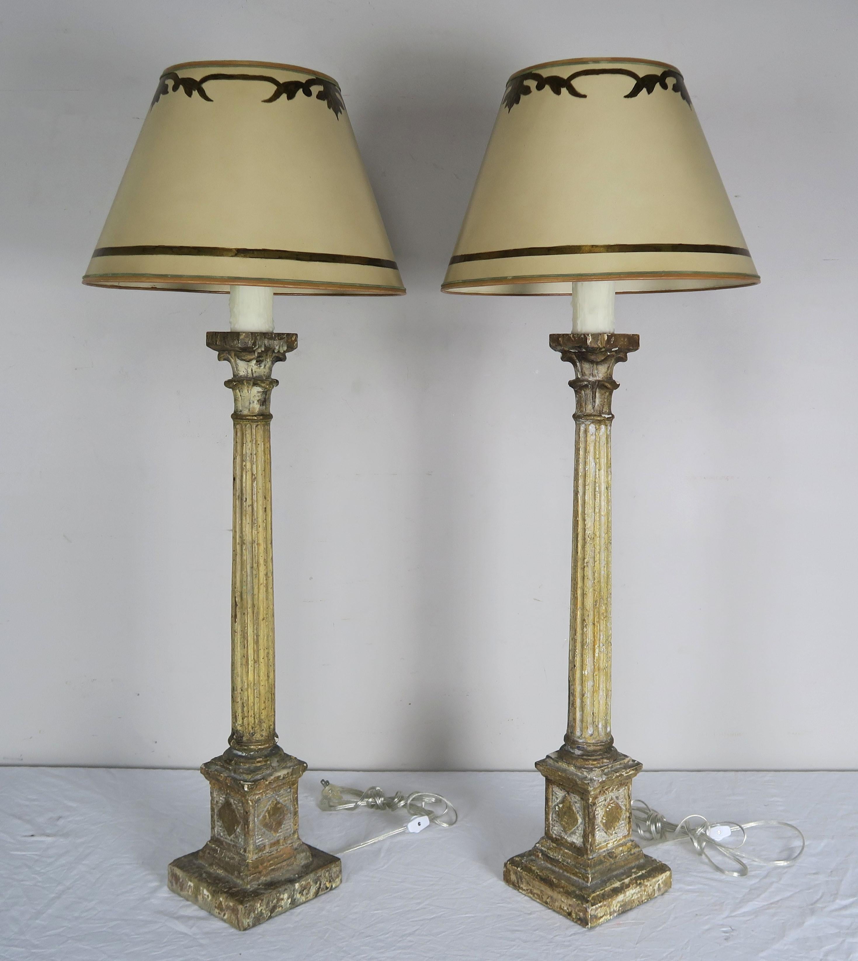 Pair of Italian neoclassical style painted carved wood candlesticks that have been wired into lamps with drip wax candle accent. The lamps are crowned with custom hand painted parchment shades.