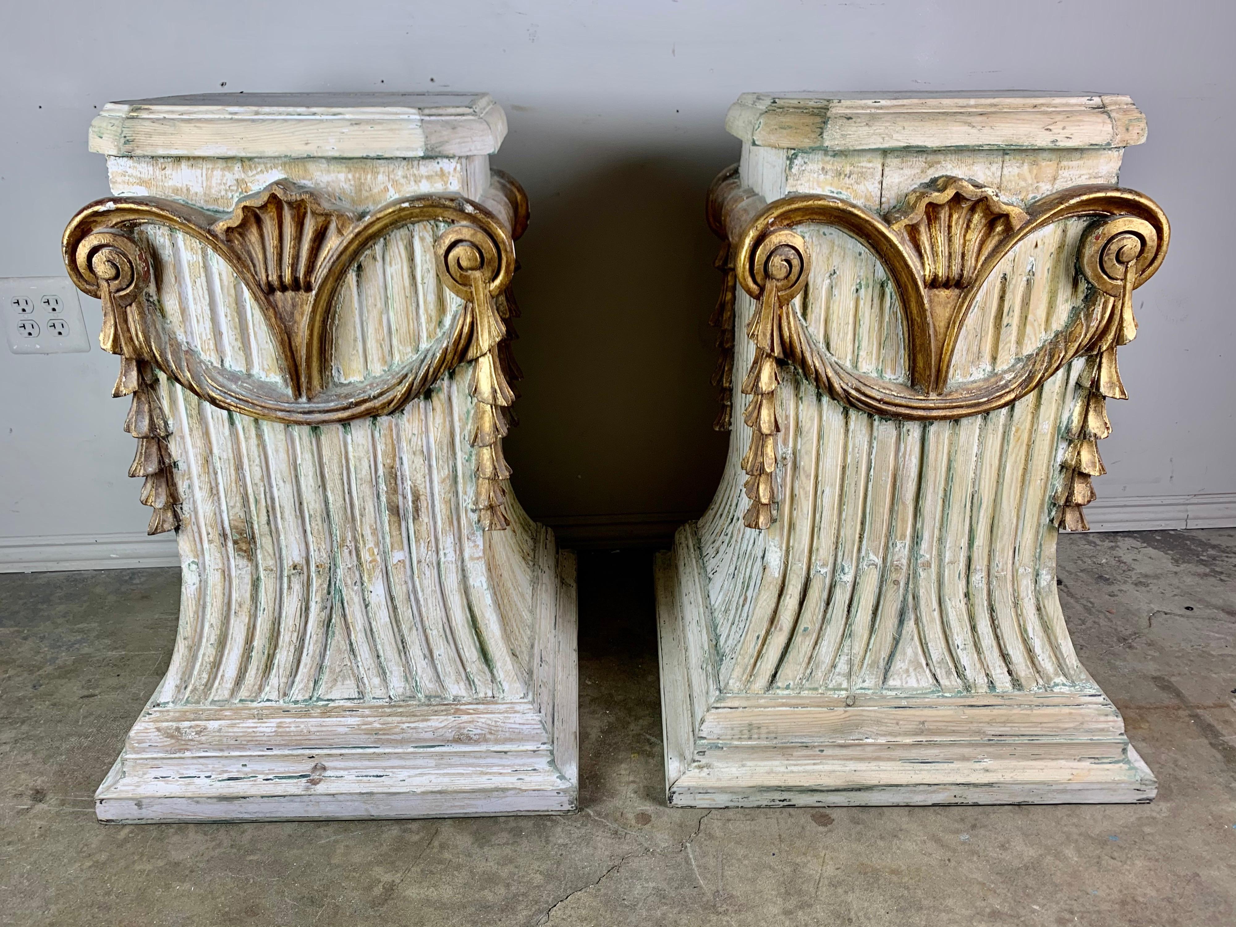Pair of Italian carved painted and parcel gilt pedestals with parcel gilt details depicting a shell motif with garlands hanging from scrolled ends.