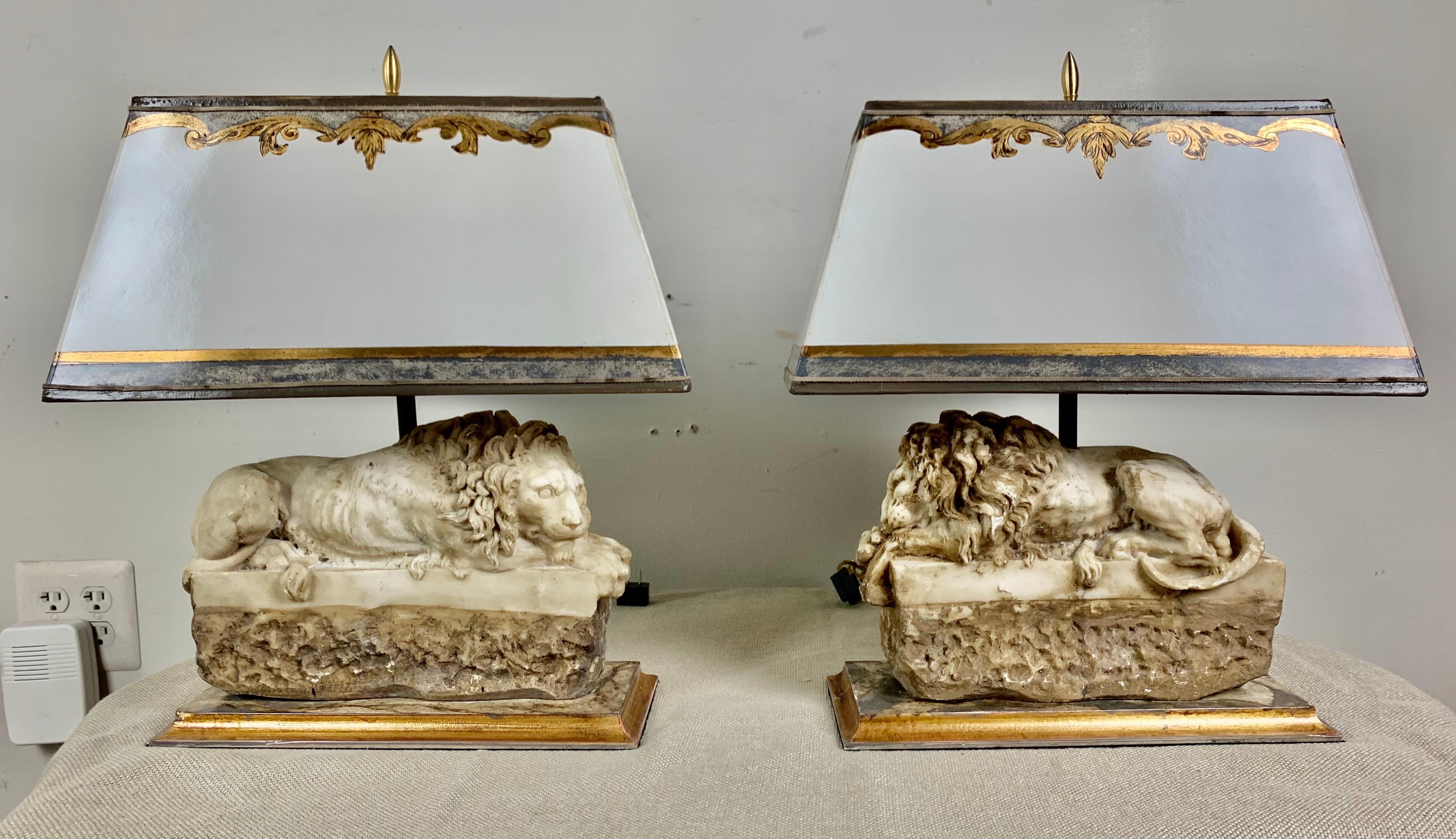 Pair of Italian carved lamps depicting lions. The antique carved lions have been mounted into lamps and sit on gilt wood rectangular bases. They are crowned with hand painted parchment shades.