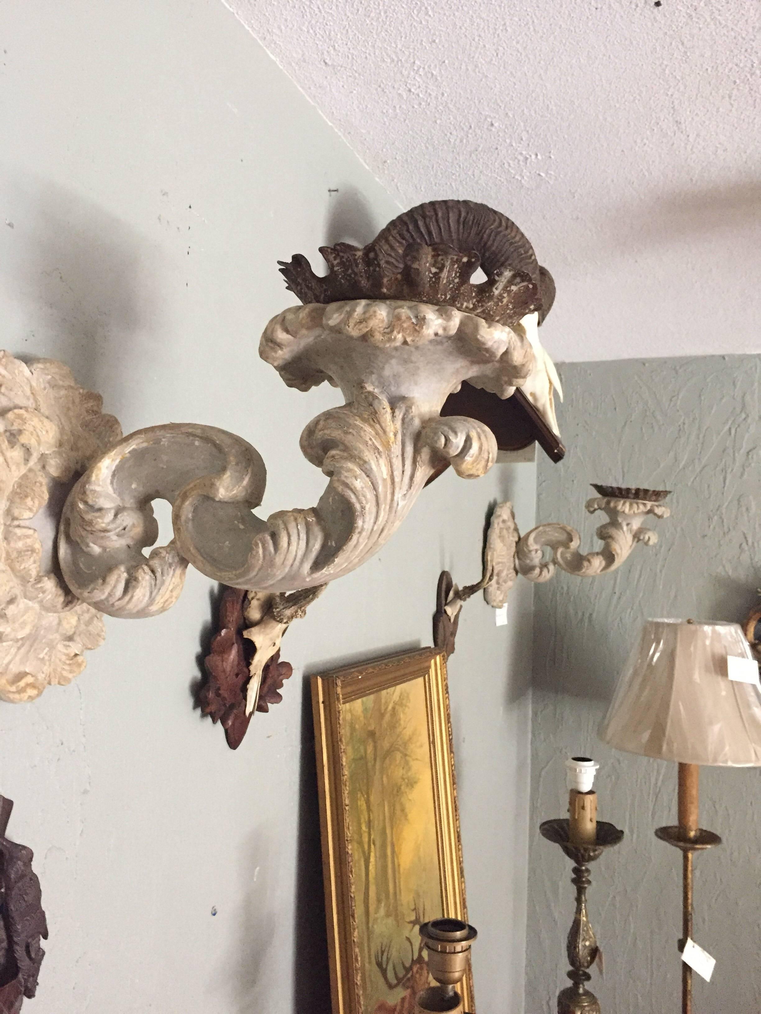 Pair of Italian carved and poly-chrome two-toned painted sconces. They are very decorative, with a deep carving, nice original patination and lovely proportions. The arms extends approximately 15 inches out from its base.