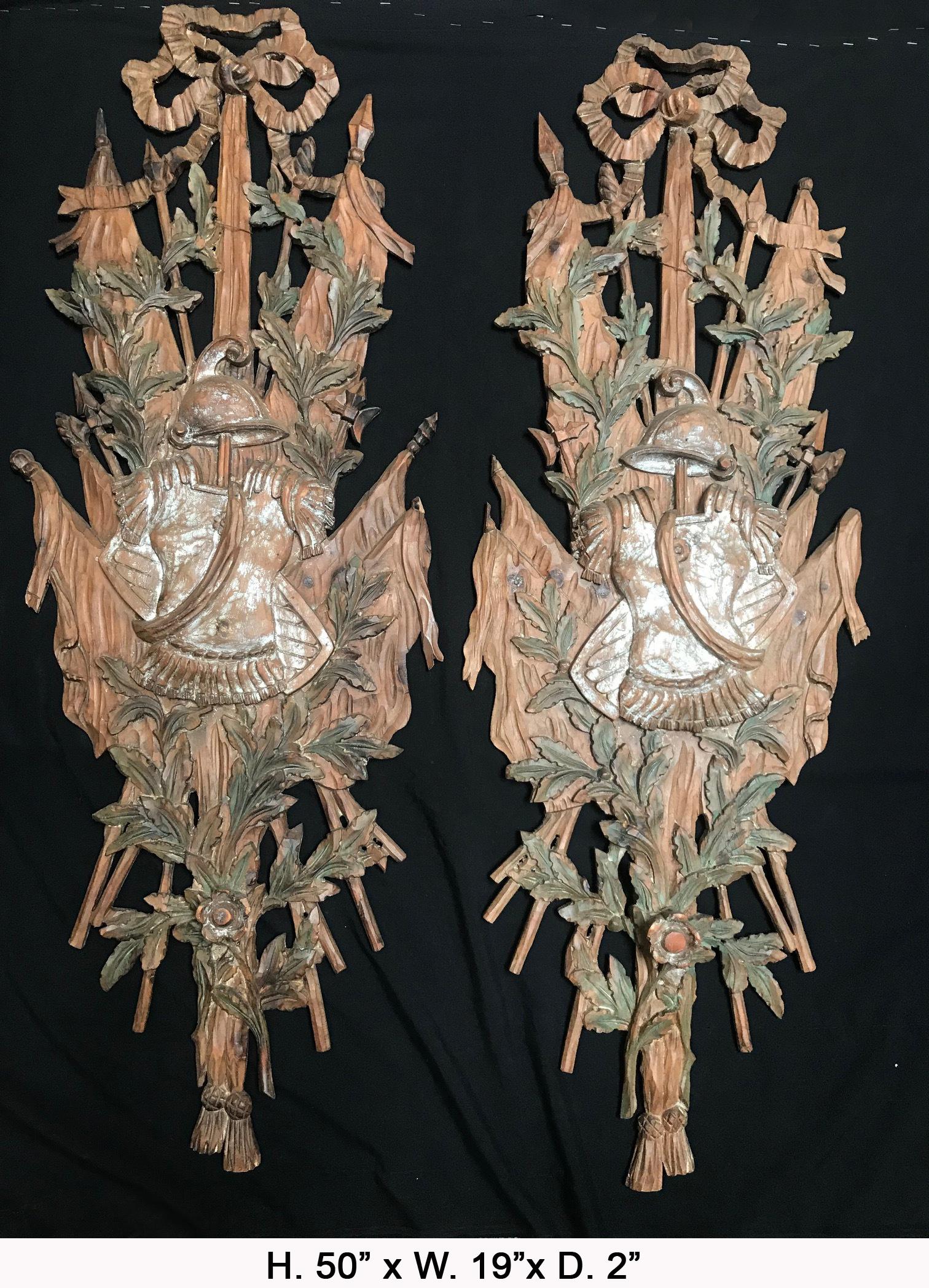 Apposing pair of Italian carved wood panels, both finely carved with ripens, flags and helmets representing coat of arms partially painted, mid-20th century.