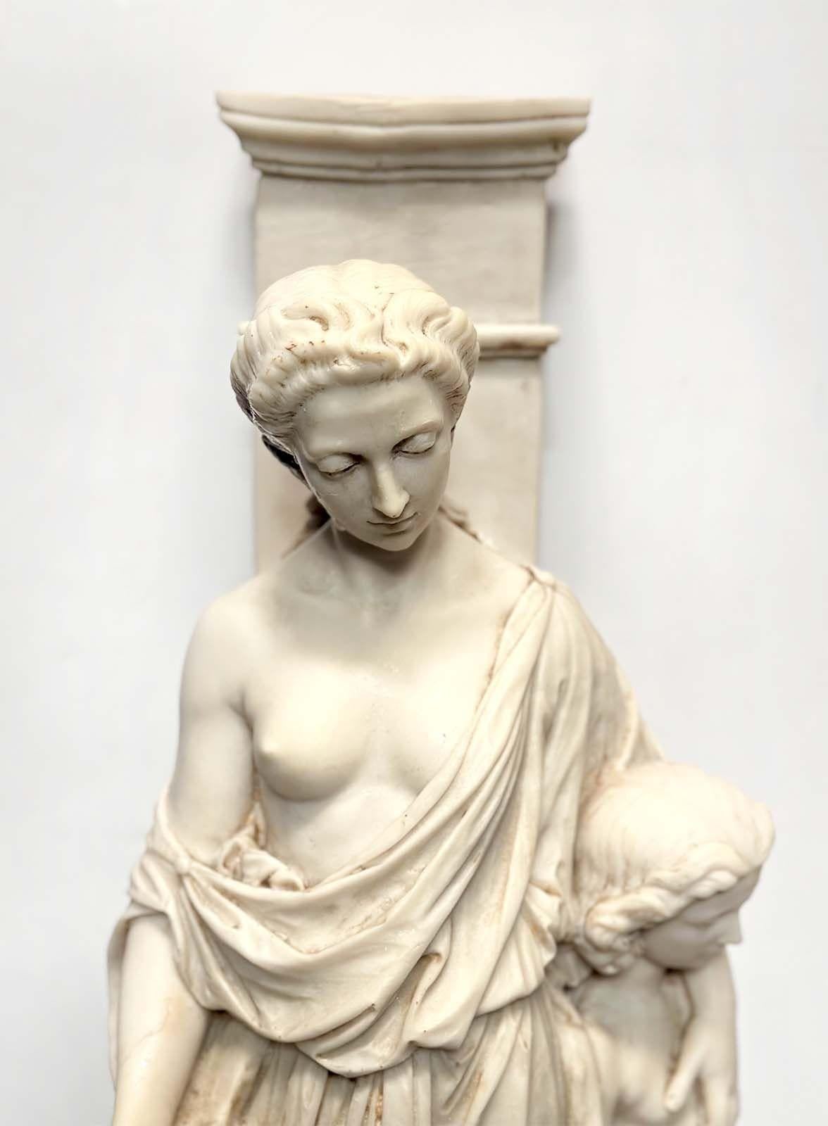 Pair of delightful white cast marble sculptures made in Italy in the 1900's capture the essence of maternal joy and the innocence of childhood. In one sculpture, a radiant woman tenderly embraces a little girl with one arm, while a playful little