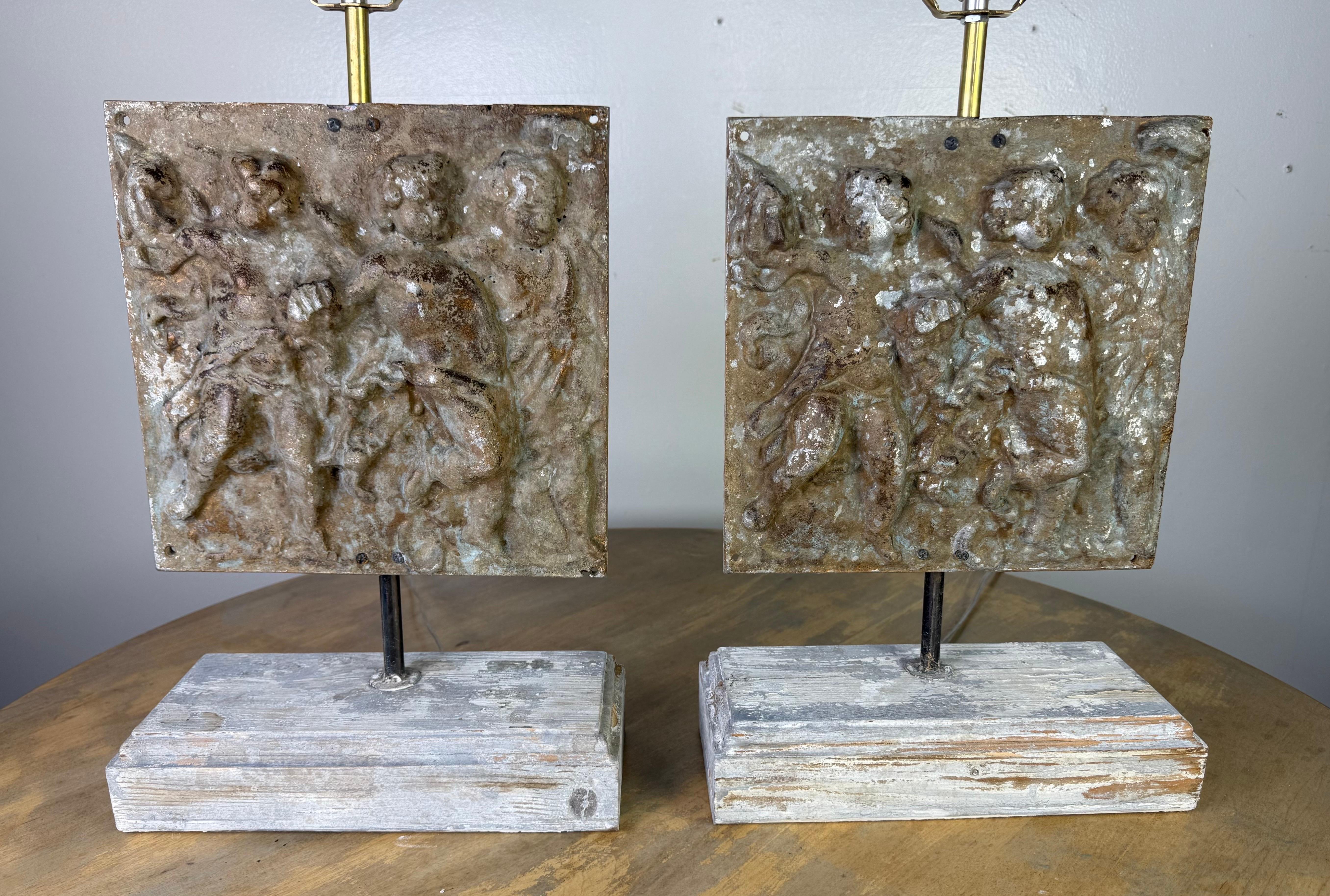 Diese einzigartigen Lampen haben als zentrales Dekorationselement gegossene Metallplaketten, die ihnen ein skulpturales und historisches Aussehen verleihen. Die rechteckigen Tafeln sind Basreliefs, die eine klassische oder mythologische Szene mit