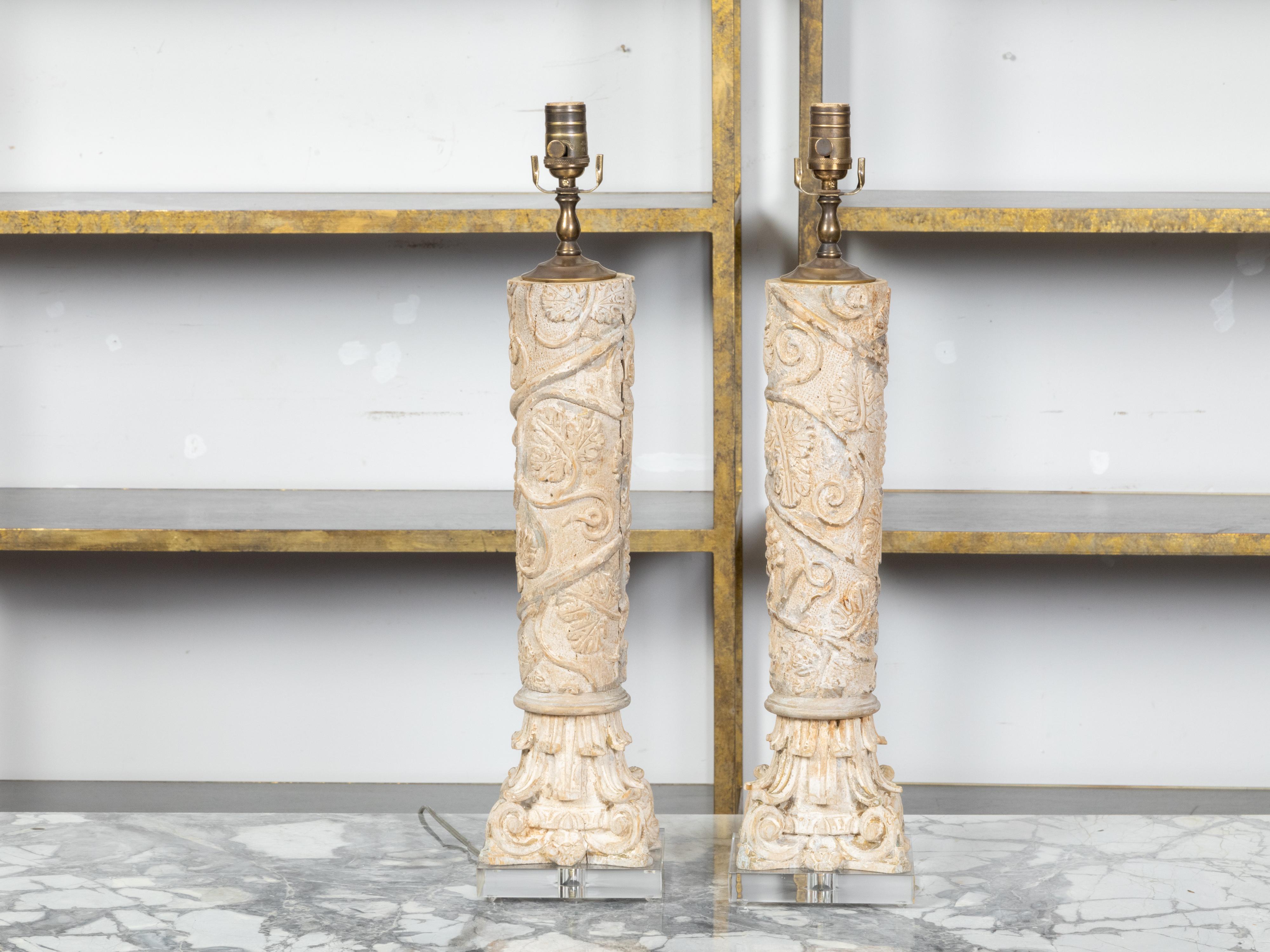 A pair of Italian Classical style carved and painted wooden column fragments from the 19th century depicting spiraling foliage and Corinthian style base, transformed into modern table lamps mounted on lucite bases. Created in Italy during the 19th