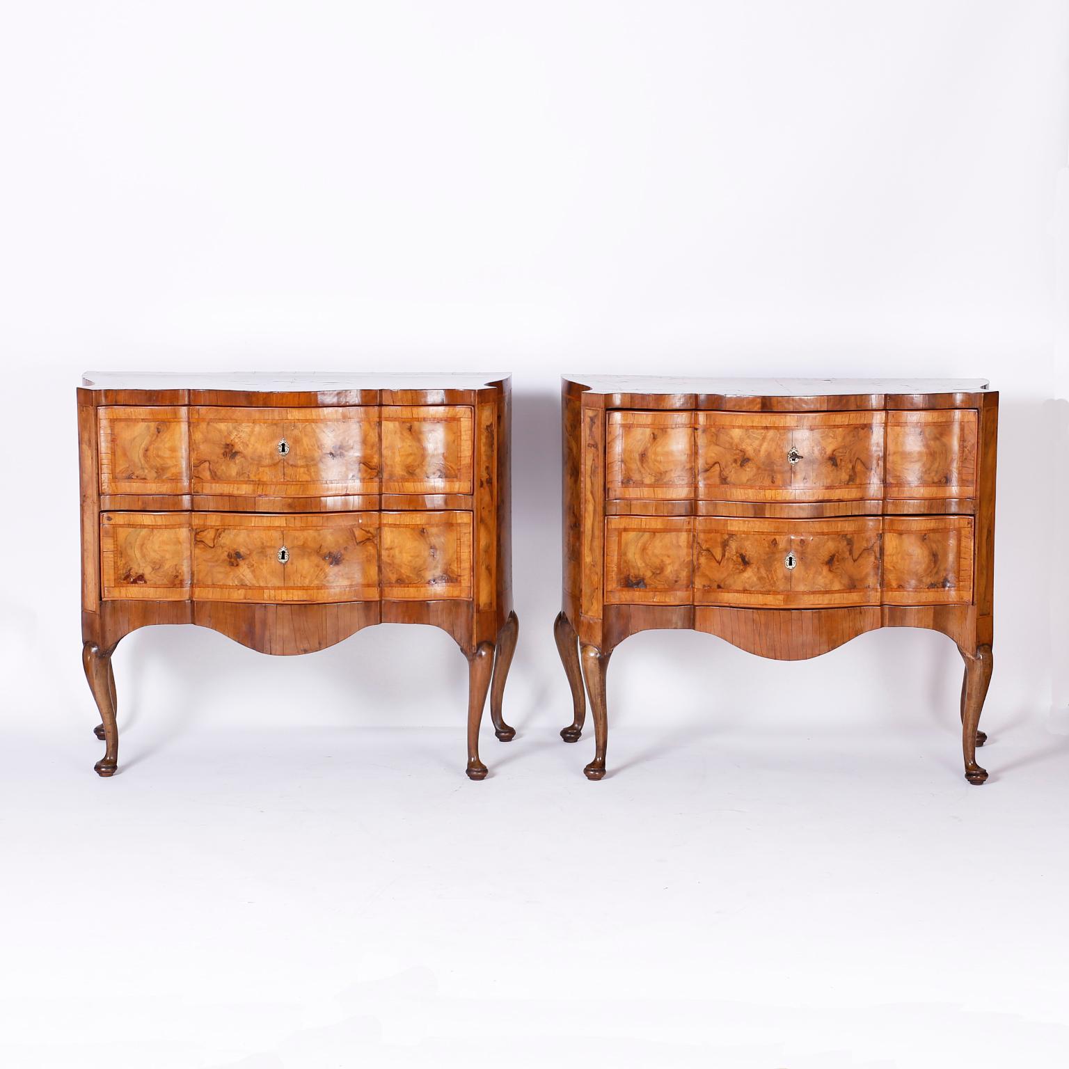 Rare pair of antique commodes crafted in walnut with dramatic burled wood grains and crossbanding. The fronts are scalloped, the sides serpentine, and the elegant cabriole legs terminate in pad feet.
