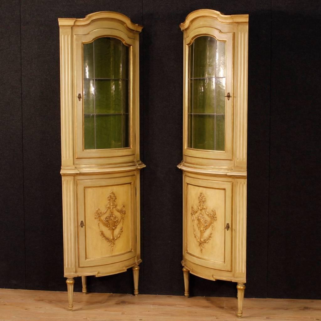 Pair of Italian corner cupboards in Louis XVI style. Furniture in richly carved, lacquered and gilded wood, of great decoration. Lower body with a door with a wooden shelf. Upper body with one door with two glass shelves of good service. Corner