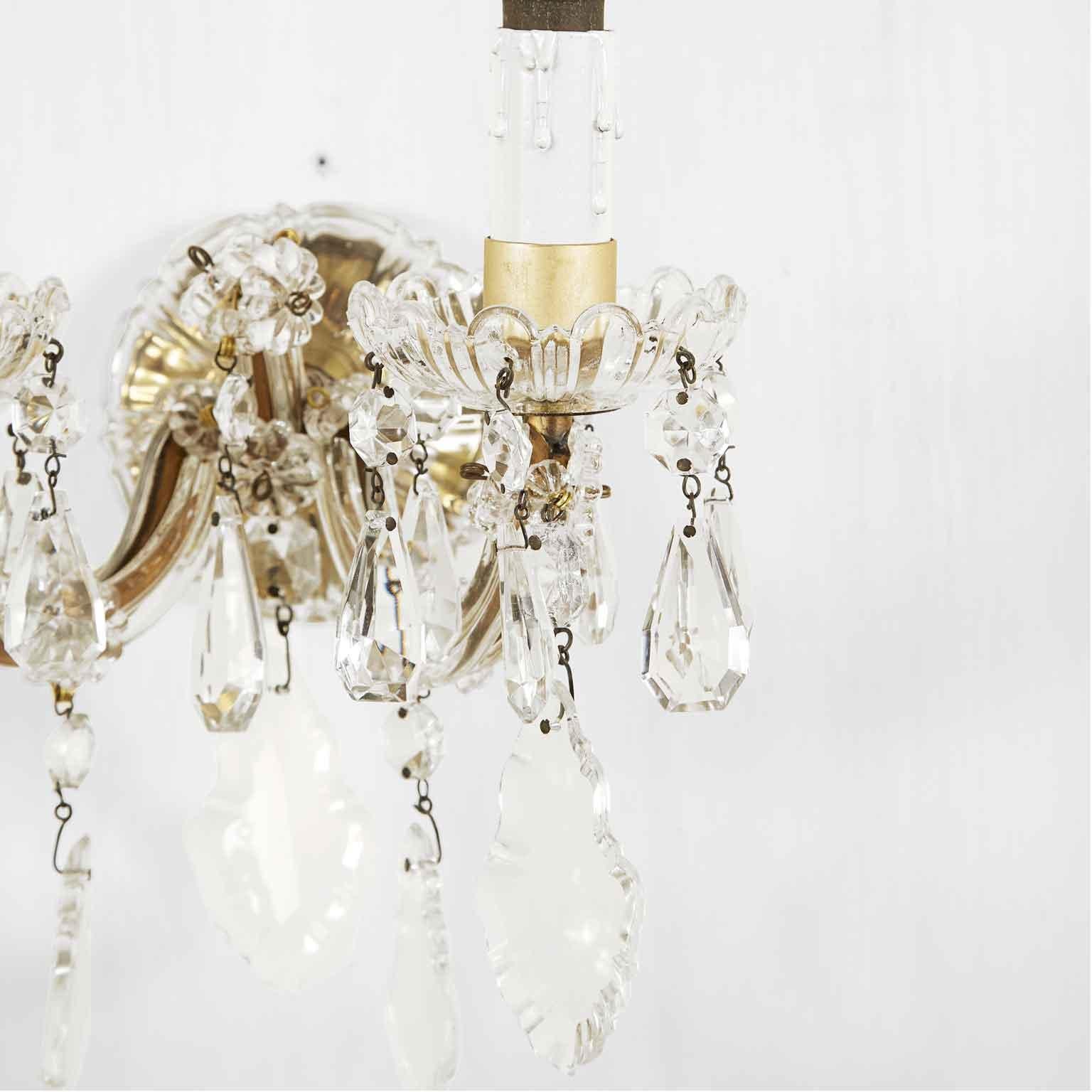 Pair of Italian Maria Therese crystal two-light sconces, coming from a private house of Milan in good condition. 
Two curved arms, fully arranged with cut glass drop shaped pendants, chains and rosettes, ending with floral cut glass bobeches. 
Of