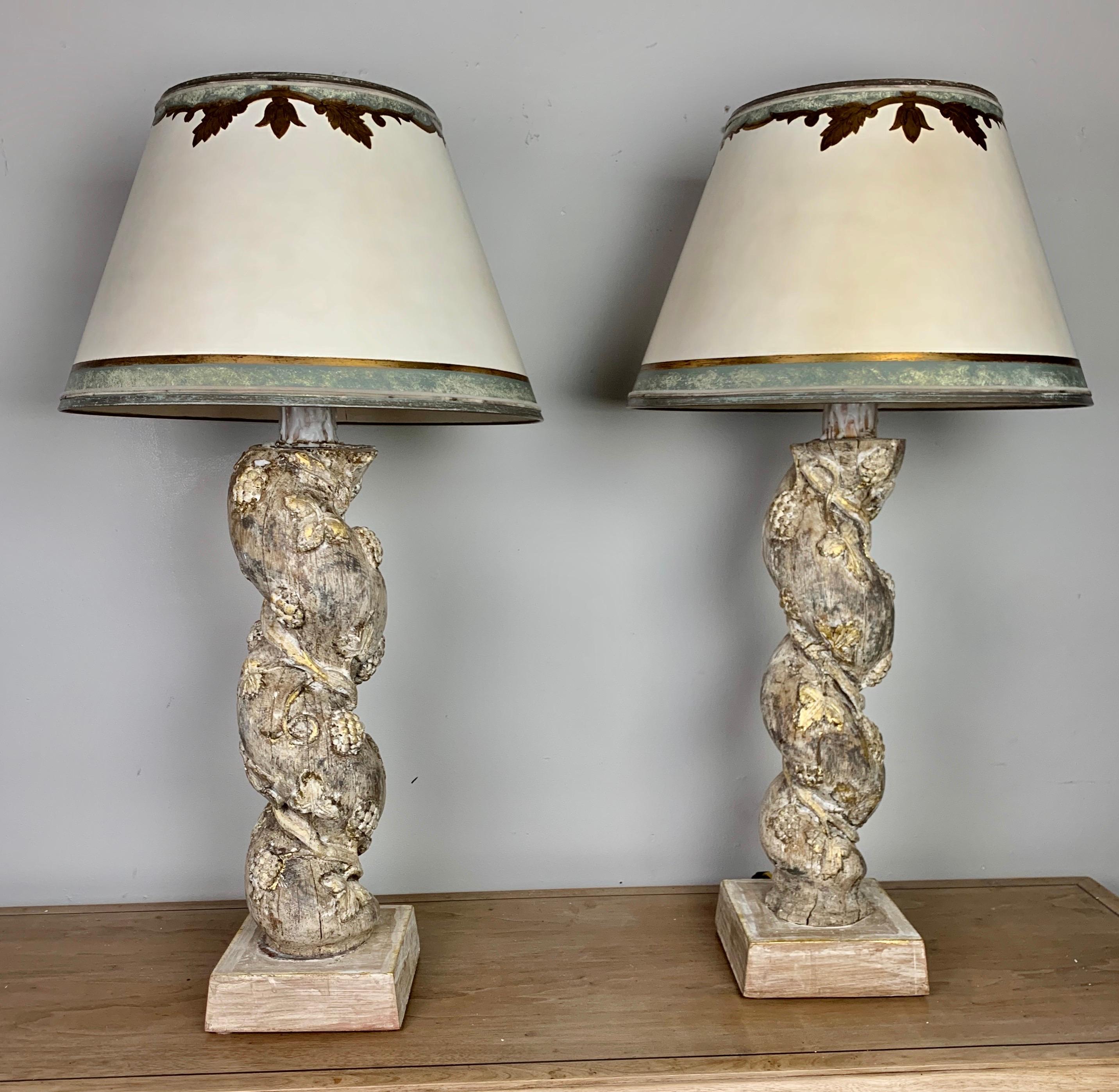 Pair of custom lamps made with a pair of 19th century twisted carved columns wired into lamps. The columns are carved with garlands of fruit and flowers. The lamps are crowned with hand painted parchment shades that are hand painted to coordinate
