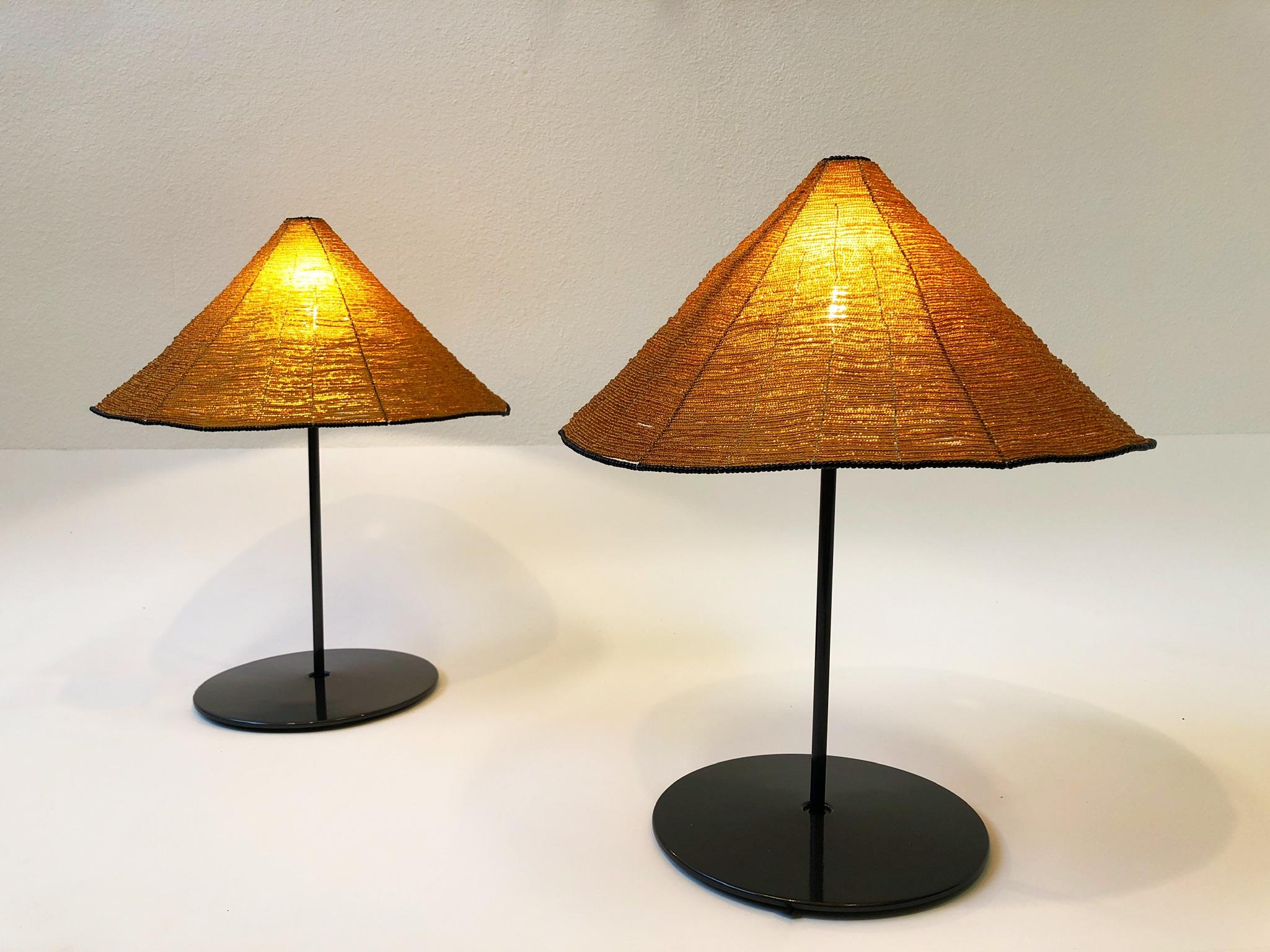 Beautiful pair of 1980s Italian table lamps designed by Roberto Pamino and Renato Toso for Leucos Design Lab.
The lamps are constructed of charcoal gray powder coated aluminum and polish brass with gold and black glass beaded shades. The bases show