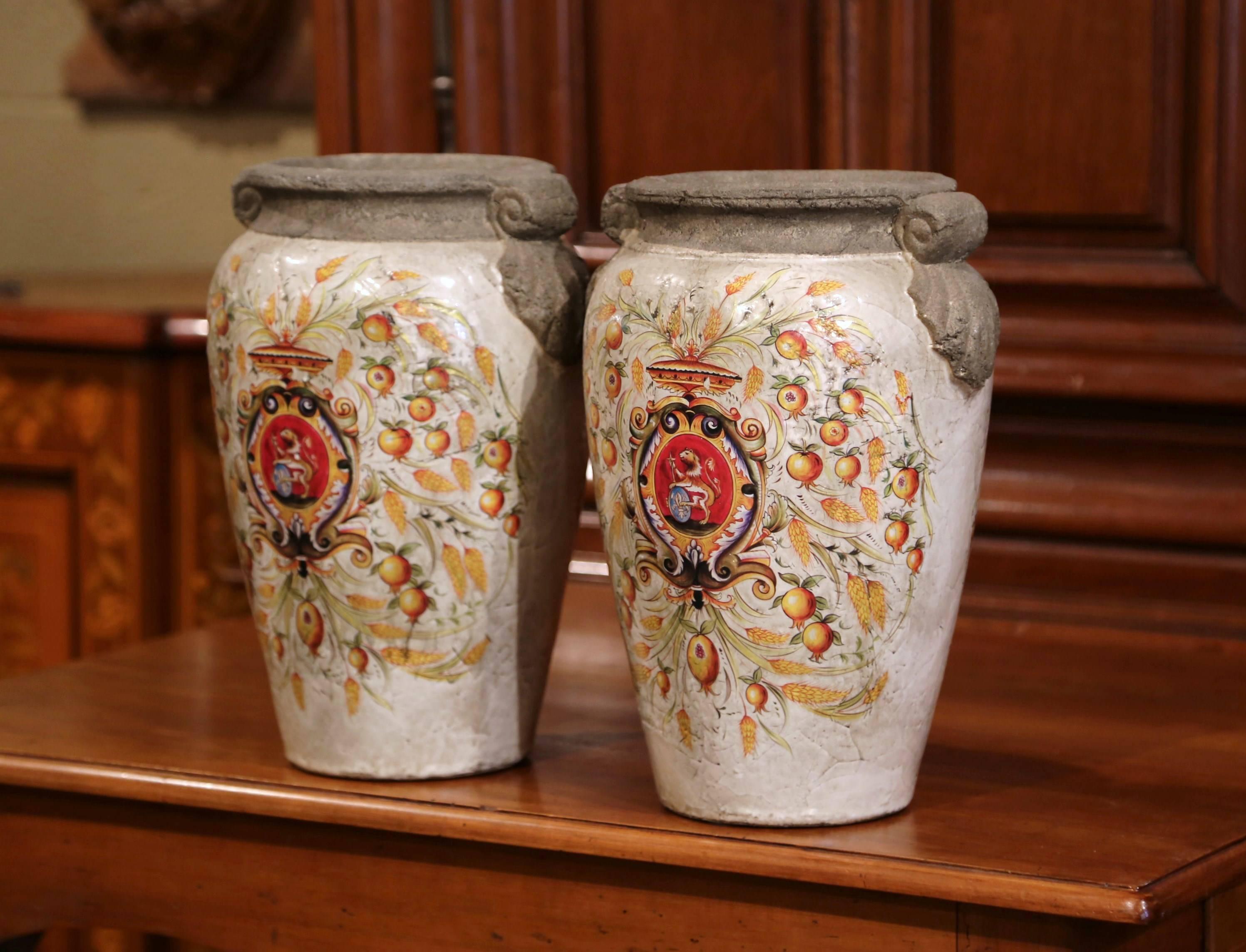 Decorate your home with this pair of colorful vases from Italy. The large, decorative vases are round in shape with small handles on either side. The ceramic vases feature hand-painted decor on both sides with a crest, wheat and fruit. The centre